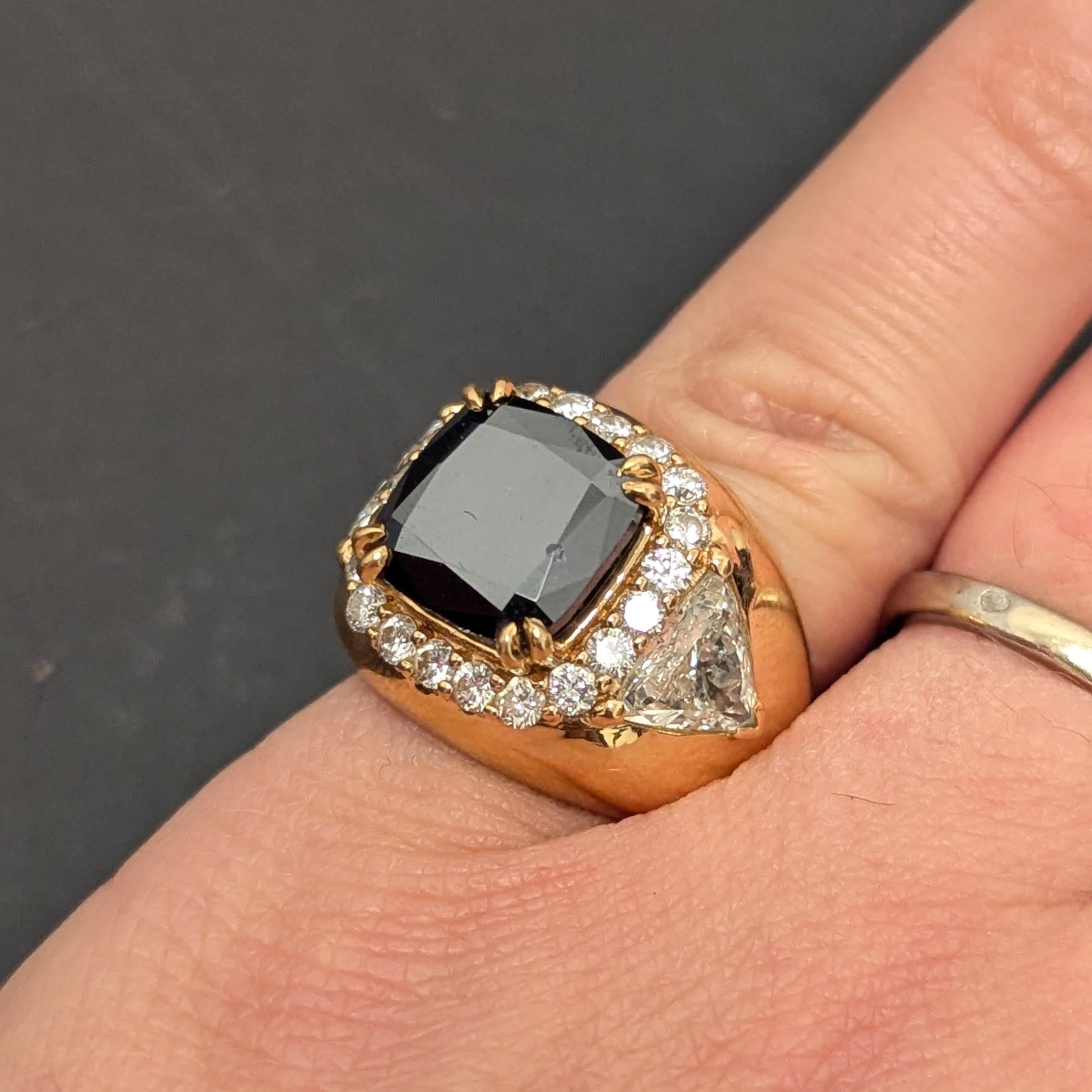 This ring features a dense black diamond, weighing approximately around 2.5cts, surrounded by round diamonds and enhanced by two, trillion-cut side diamonds, each weighing approximately 1ct, set in 18K yellow gold.

There is a debate as to whether