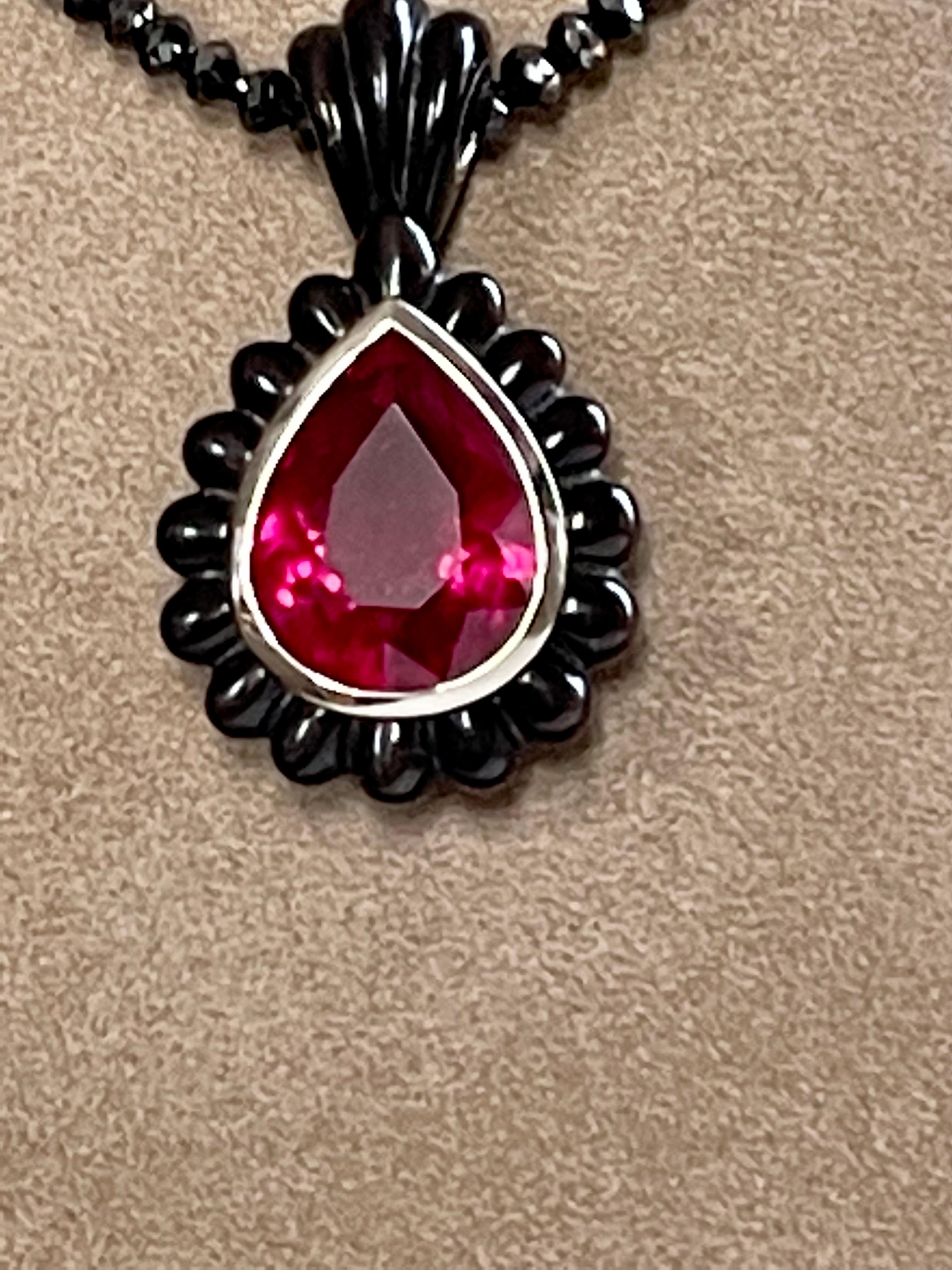 A necklace of briolette-cut black diamond beads weighing 28.4 ct featuring a handcarved Horn and 18 K white Gold pendant set with a colorful pear shape Rubelite weighing 14.54 ct. 
A very dramatic and decorative necklace with Pendant. 
Length of