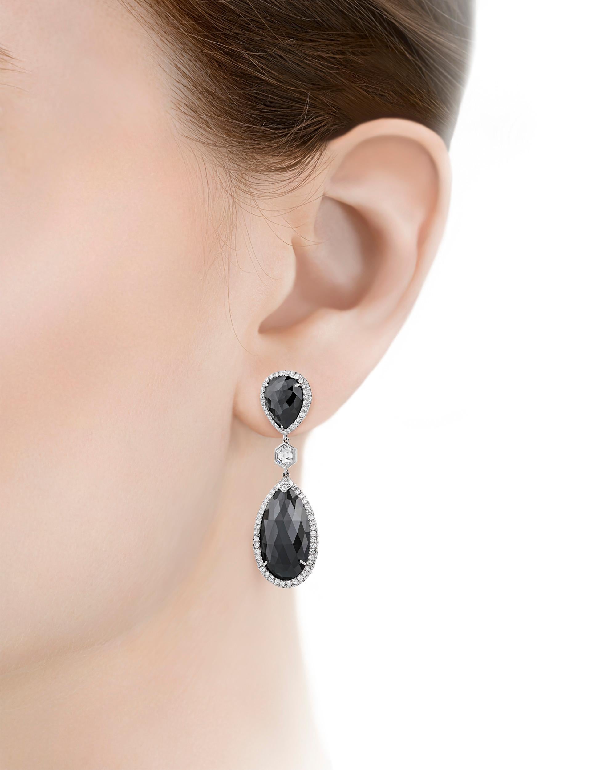 Dramatic yet elegant, these drop earrings feature four alluring black diamonds totaling approximately 32.00 carats. Held within a sophisticated 18K white gold setting accented with approximately 3.50 carats of sparkling white diamonds, these
