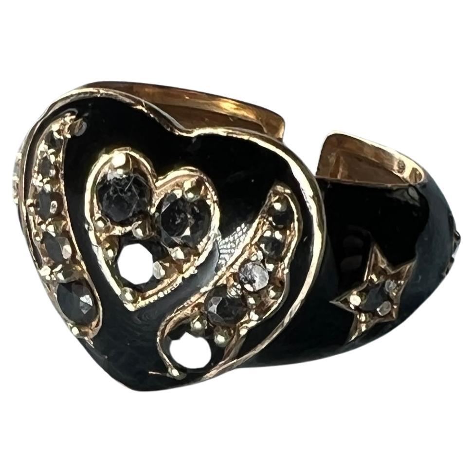 Black Diamond Heart Ring Enamel 

Designer: J Dauphin

Heart Ring with several Single Cut Black Diamonds hand painted with Black Enamel, on the side of the central hearts it has angel wings and on the band there are two stars on each side also set