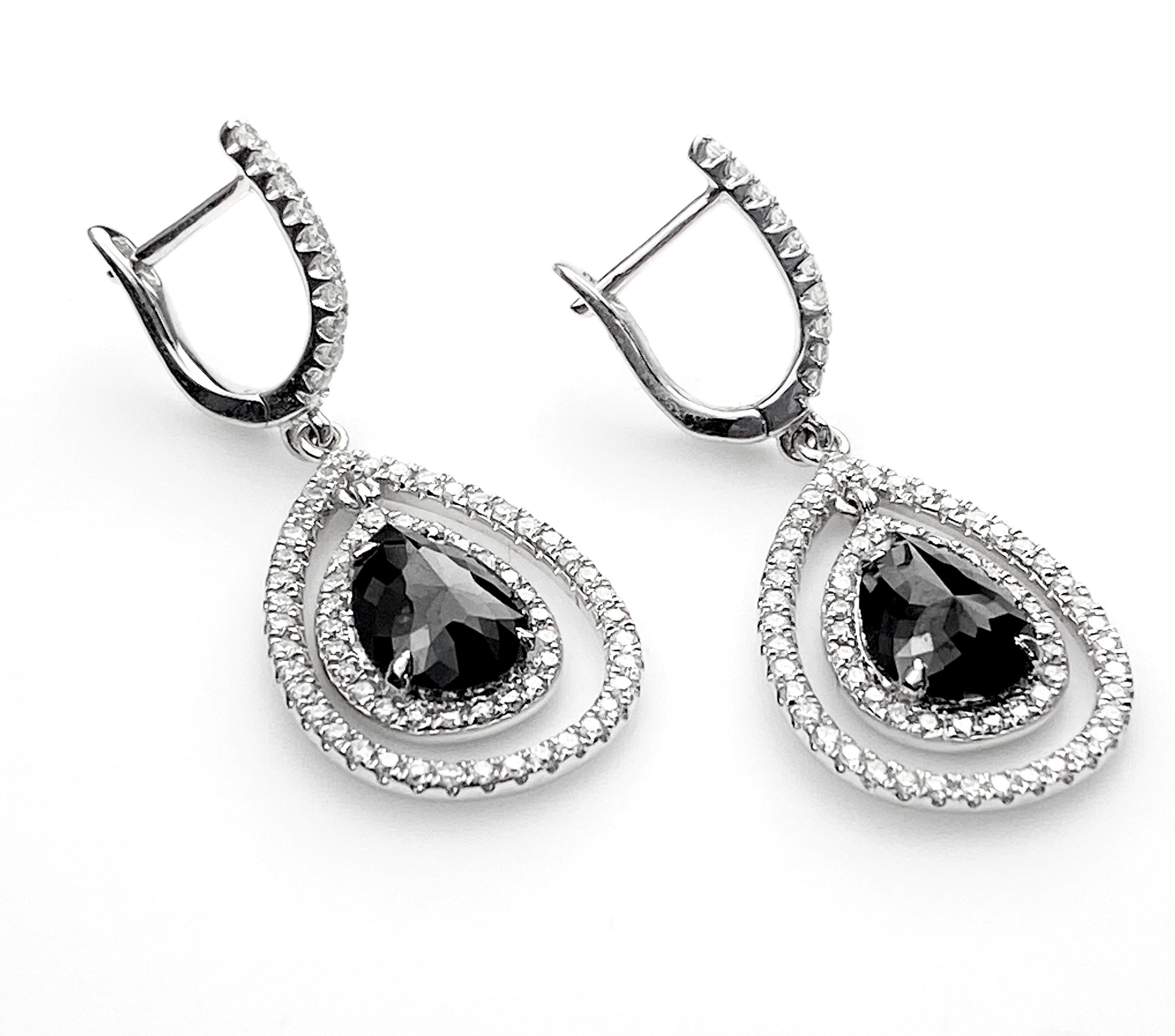 Elegant drop earrings featuring two pear-cut black diamonds equal 3.09ct total. Surrounded by a double halo of 0.78ct total of round brilliant white diamonds. Completed with post and hinge closures on 14kt white gold lever backings.
