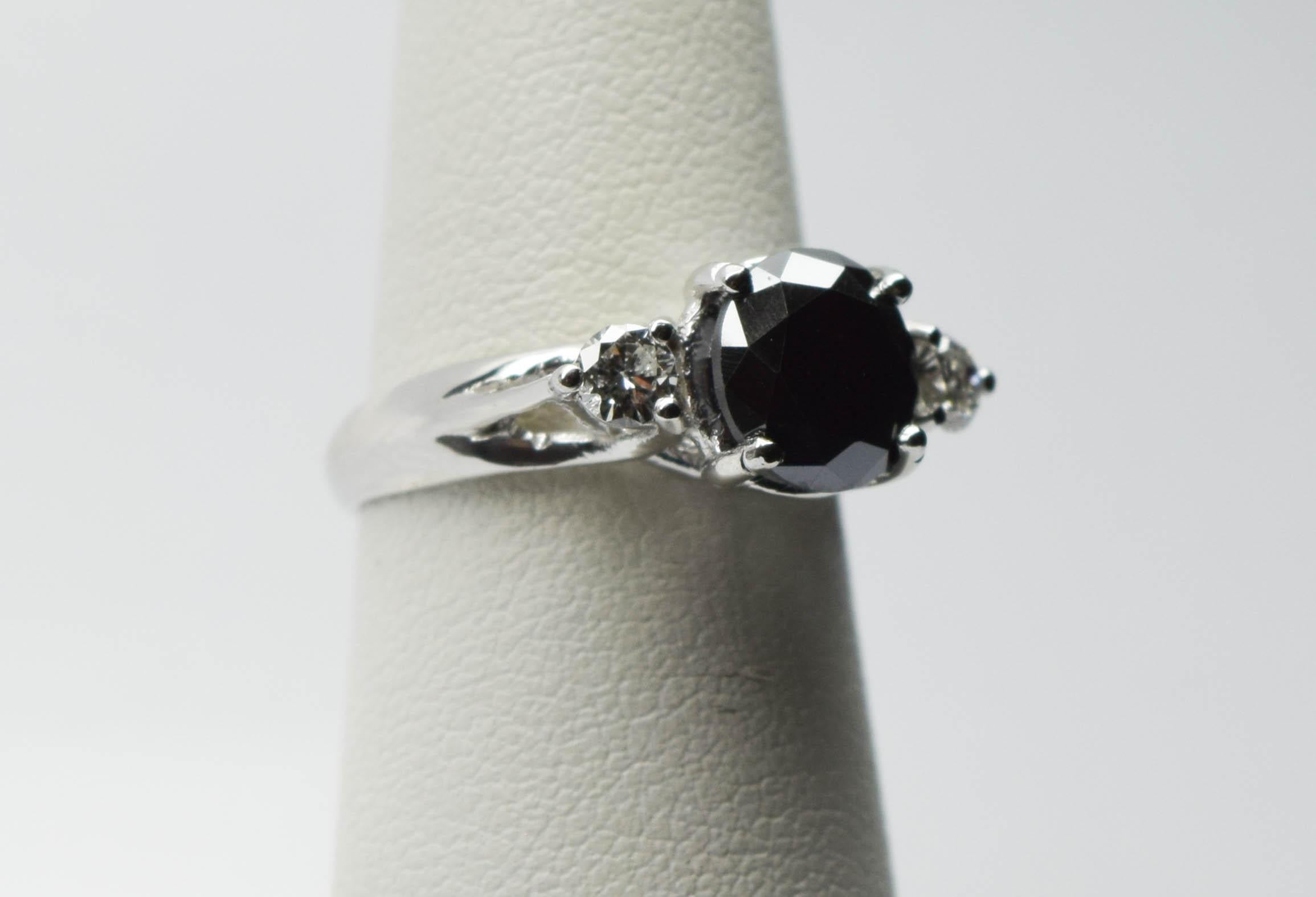 What a beautiful three stone ring featuring center black diamond 2 carats and side diamonds 0.20ct each. The center diamond is a certified black diamond not man made not treated 100% natural, side daimonds are white diamonds VS-SI clarity and G-H