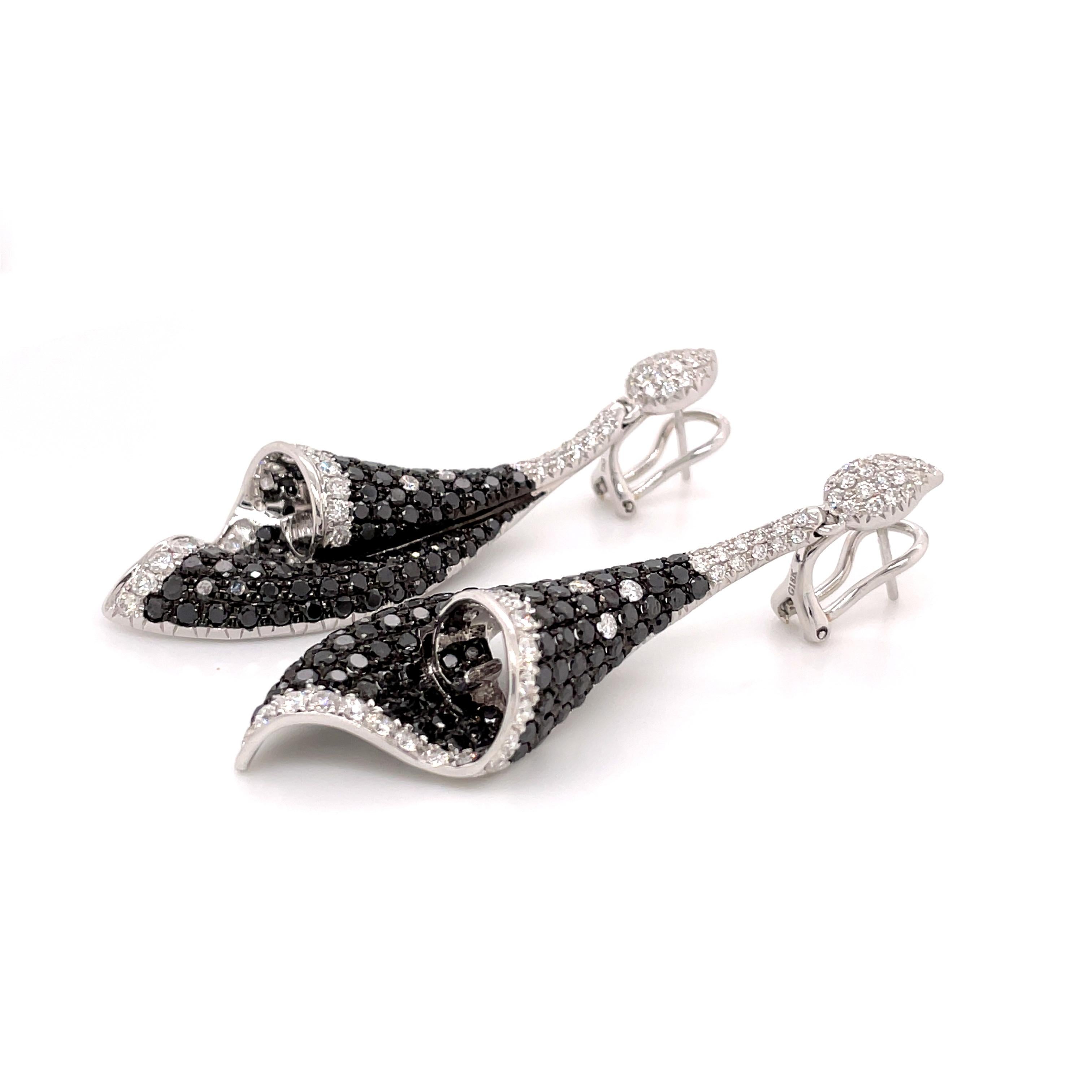 These elegant conch shell earrings showcase a striking contrast between black and white diamonds, creating a harmonious blend of sophistication and allure. The outer curves of the conch shell are studded with shimmering white diamonds, adding a