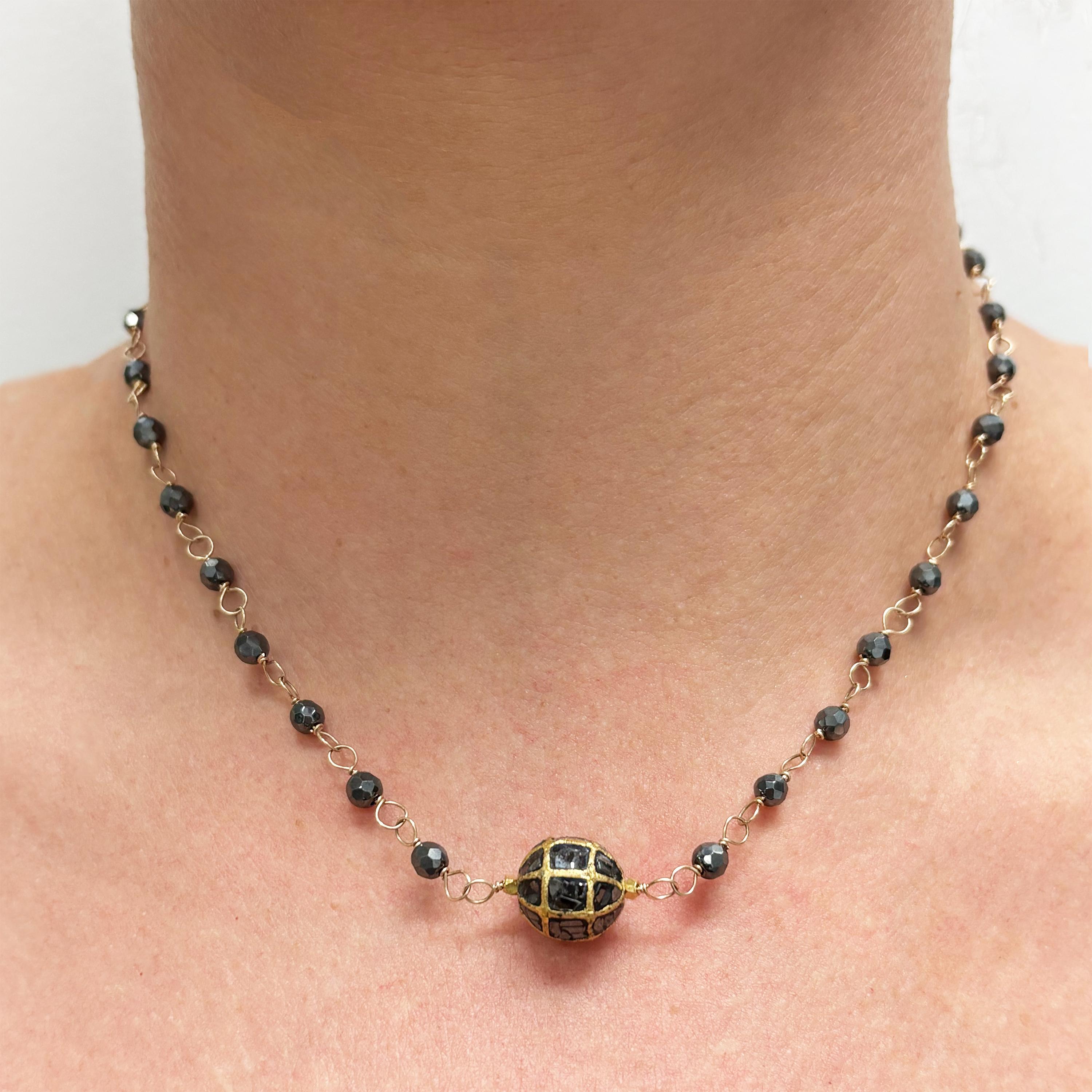 Descripción
Los diamantes negros encerrados en una esfera de oro de 18 quilates con motivos geométricos están flanqueados por radiantes cuentas facetadas de 20 quilates y acentuados con hematites meticulosamente enroscada a mano. Una composición