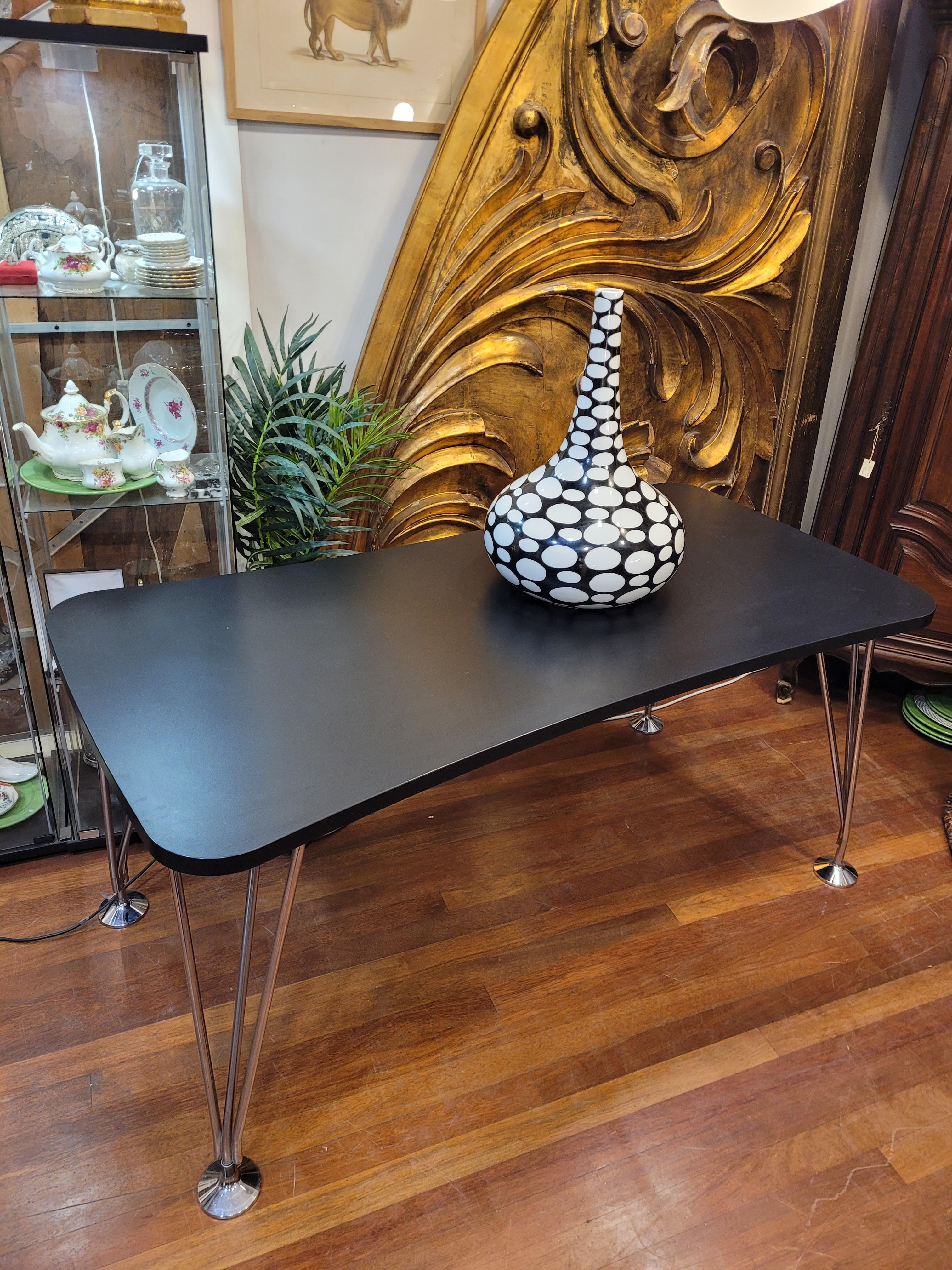 Étonnante table à la mode conçue par Piet Hein & Bruno Mathsson pour la maison Frits Hansen, fabriquée dans les années 1960 au Danemark. Le plateau est en bois laqué noir et les pieds en acier chromé. Extrêmement simple et épurée, cette table est