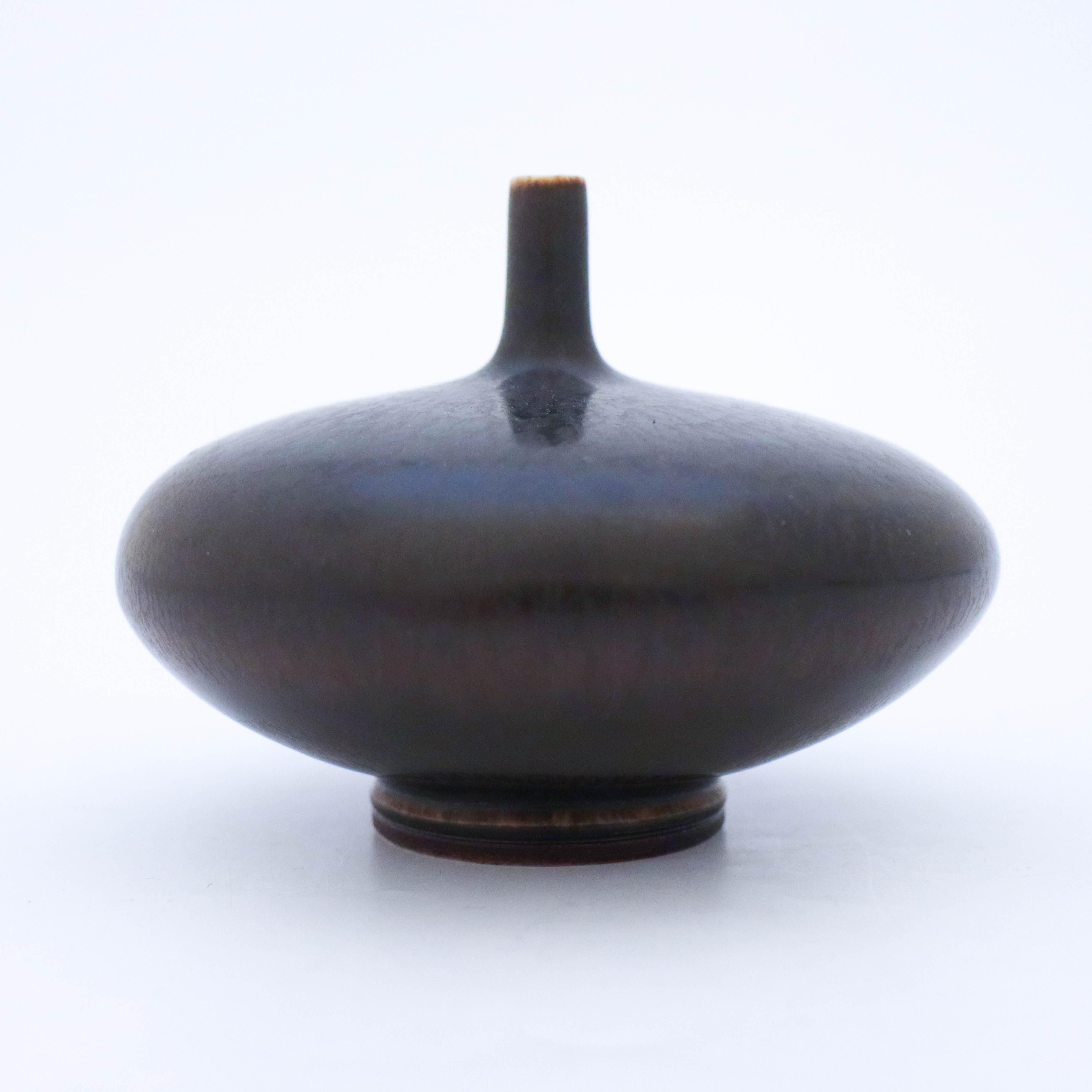 A black discus vase designed by Berndt Friberg at Gustavsberg. It is 9.5 cm high and 12.5 cm in diameter and in very good condition except from a tiny white mark in the glaze. It´s marked as the picture shows, this one is produced in 1967.