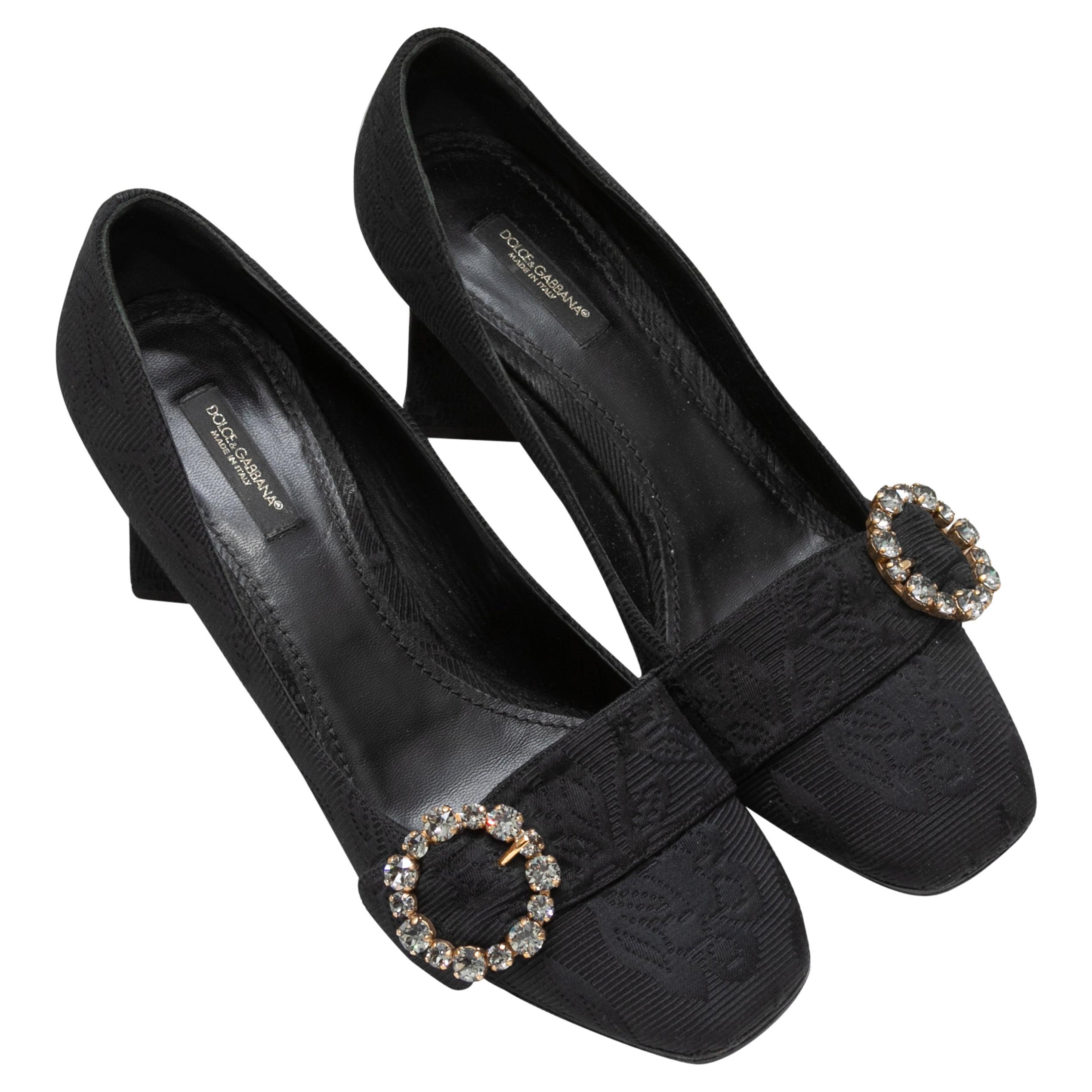 Black jacquard block heel pumps by Dolce & Gabbana. Crystal buckle adornments at tops. 2.375
