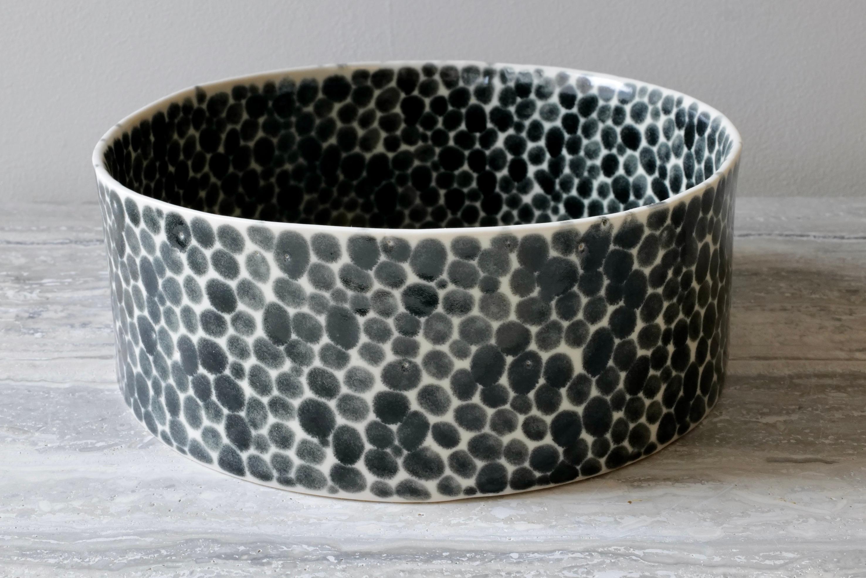 This multi-functional bowl is perfect for fruits or vegetables or for serving food. Hand-cast in porcelain and once bisque fired, each dot is hand-painted using a shiny black glaze. An unconventional layered glazing technique, developed by the