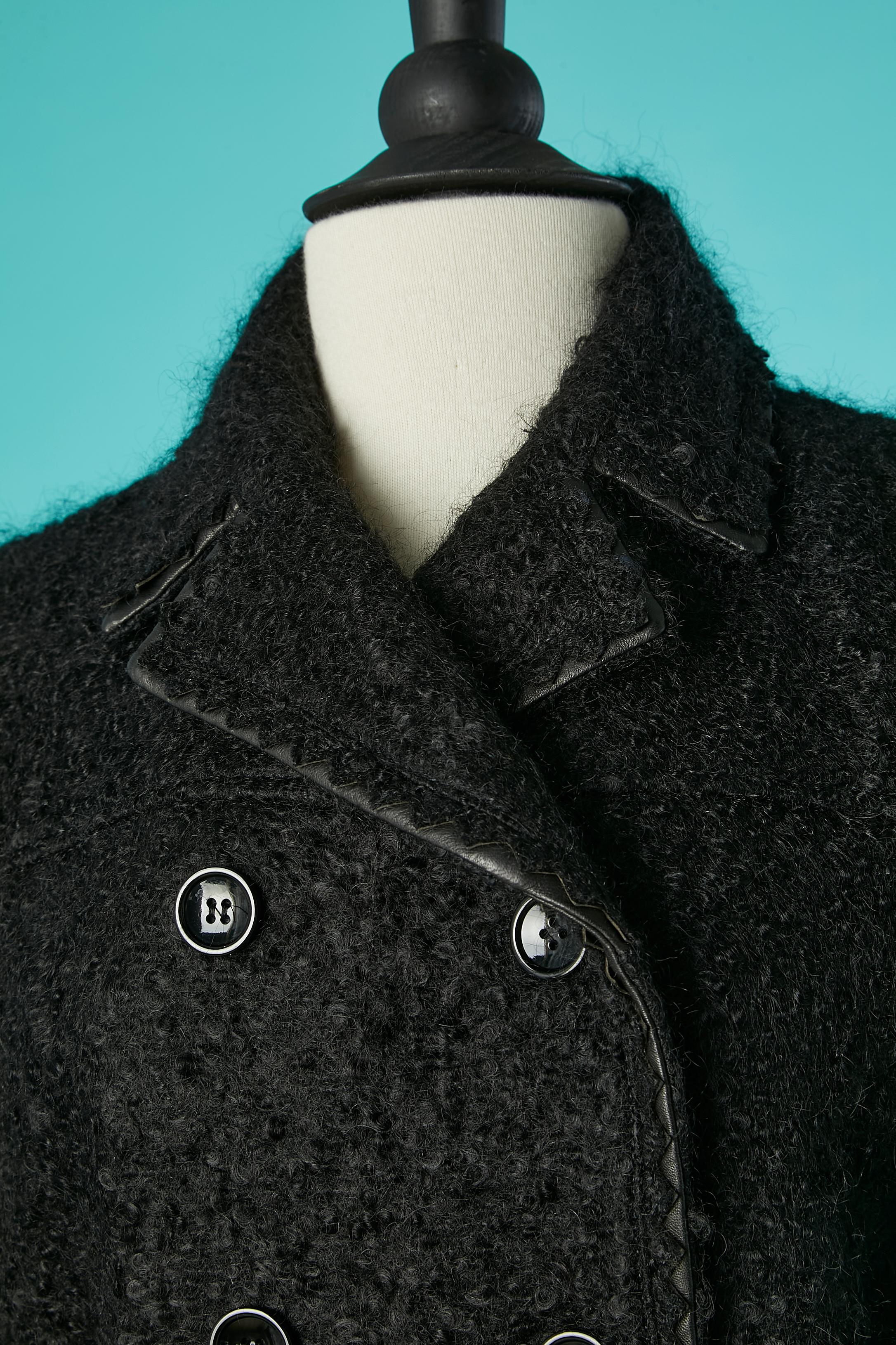Manteau en laine bouclette noire à double boutonnage avec passepoil en cuir. Composition du tissu : 51% mohair, 41% laine, 7% polyamide, 1% lycra.
Doublure de marque : 65% rayonne, 35% soie. 
Epaule fine. Ceinture et boucle. Poches. 
TAILLE 44 (It)