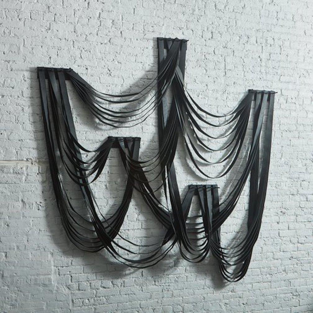 A large-scale wall sculpture made from recycled rubber by Canadian artist Erin Vincent. This captivating piece features layers of textured rubber straps which hang in tiered drapes from five sleek iron supports.

Erin Vincent is a Canadian artist