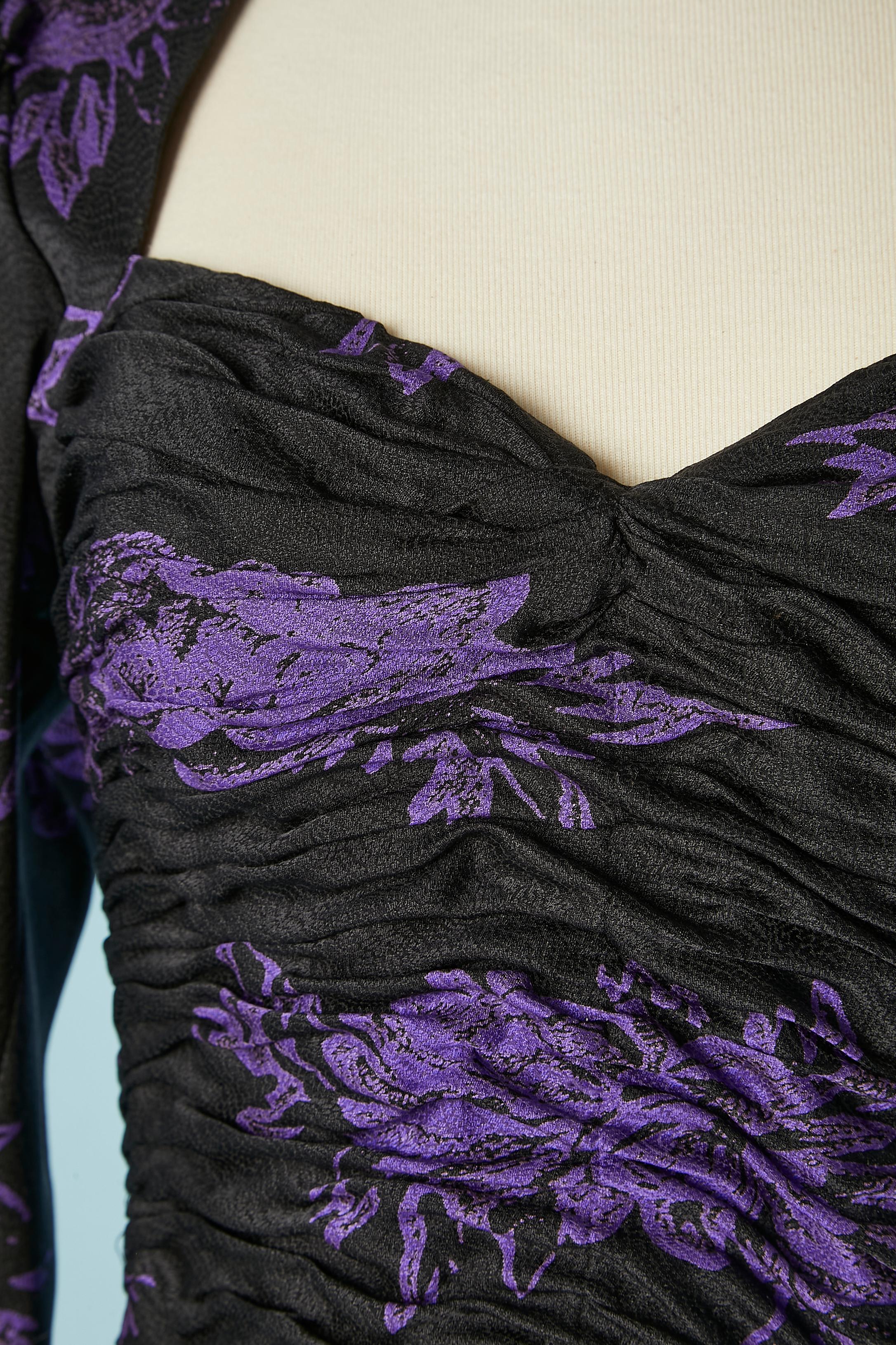  Black cocktail dress with purple flower jacquard.Boned middle front and side. Zip, hook&eye and on button middle back. Pleated ruffles. Zip on cuff., lenght= 12 cm .Shoulder pad. 
SIZE 10