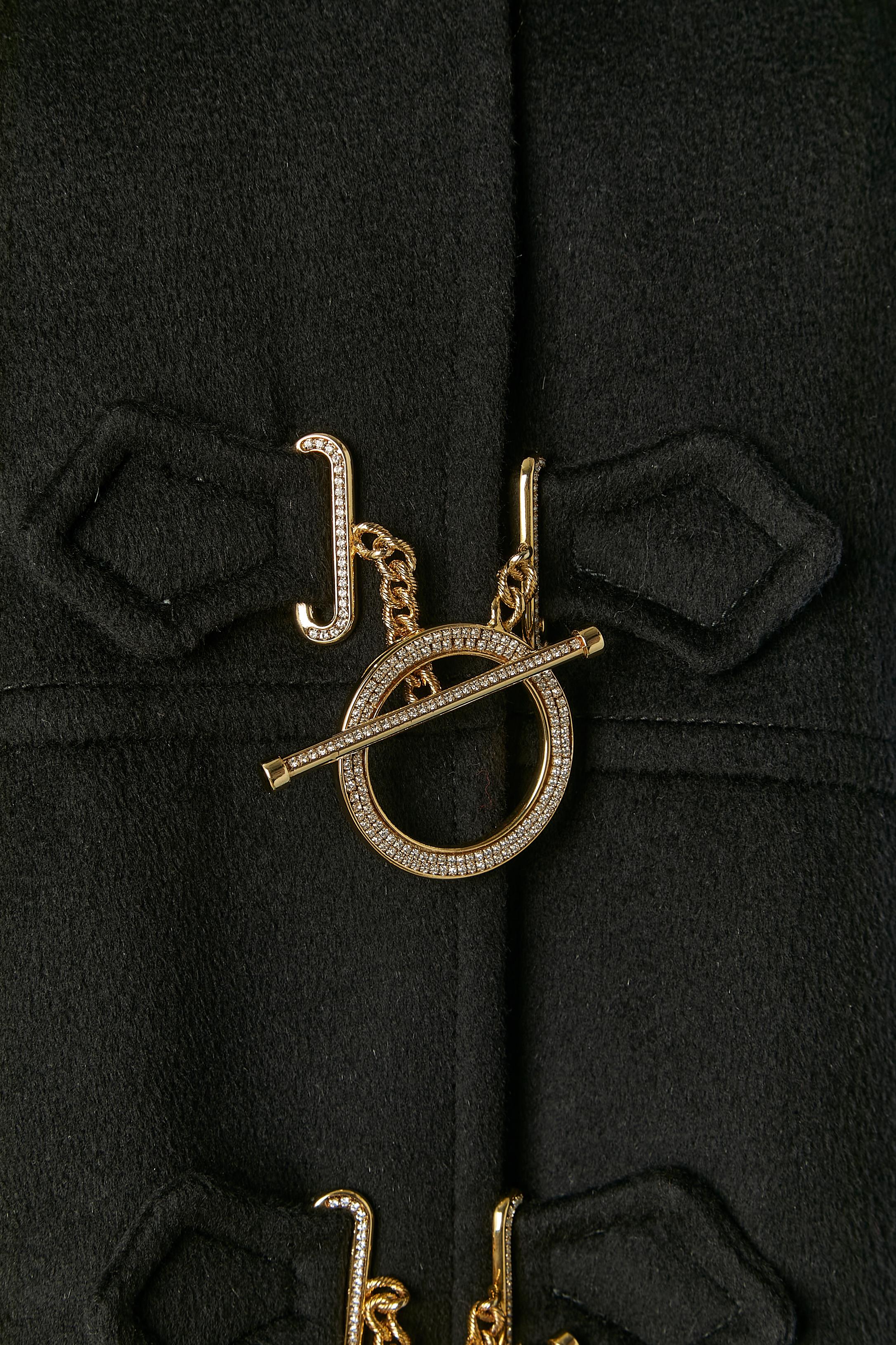 Black duffle-coat with hood with fur (Fox) edge.
Fabric composition: 60% wool, 30% angora, 10% cashmere. Branded Lining: 68% acetate, 32% polyester. Detachable hood with button and buttonhole. Gold metal ring closure with rhinestone embellishment.