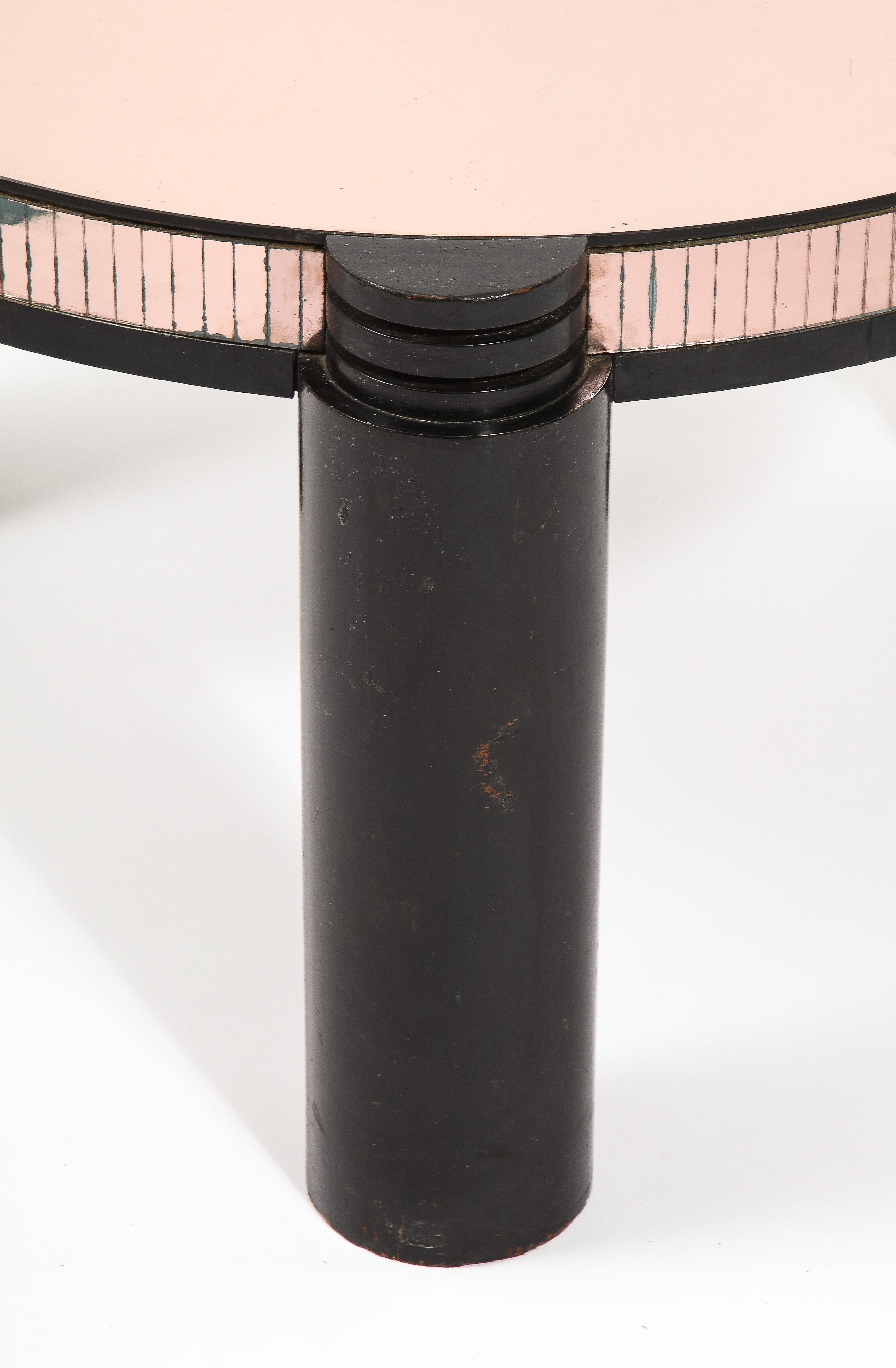 A round ebonized wood cocktail table with a pink mirrored top and edge, the legs have a grooved motif and are rounded on the outside. The table is in its original finish and can be fully restored on request.