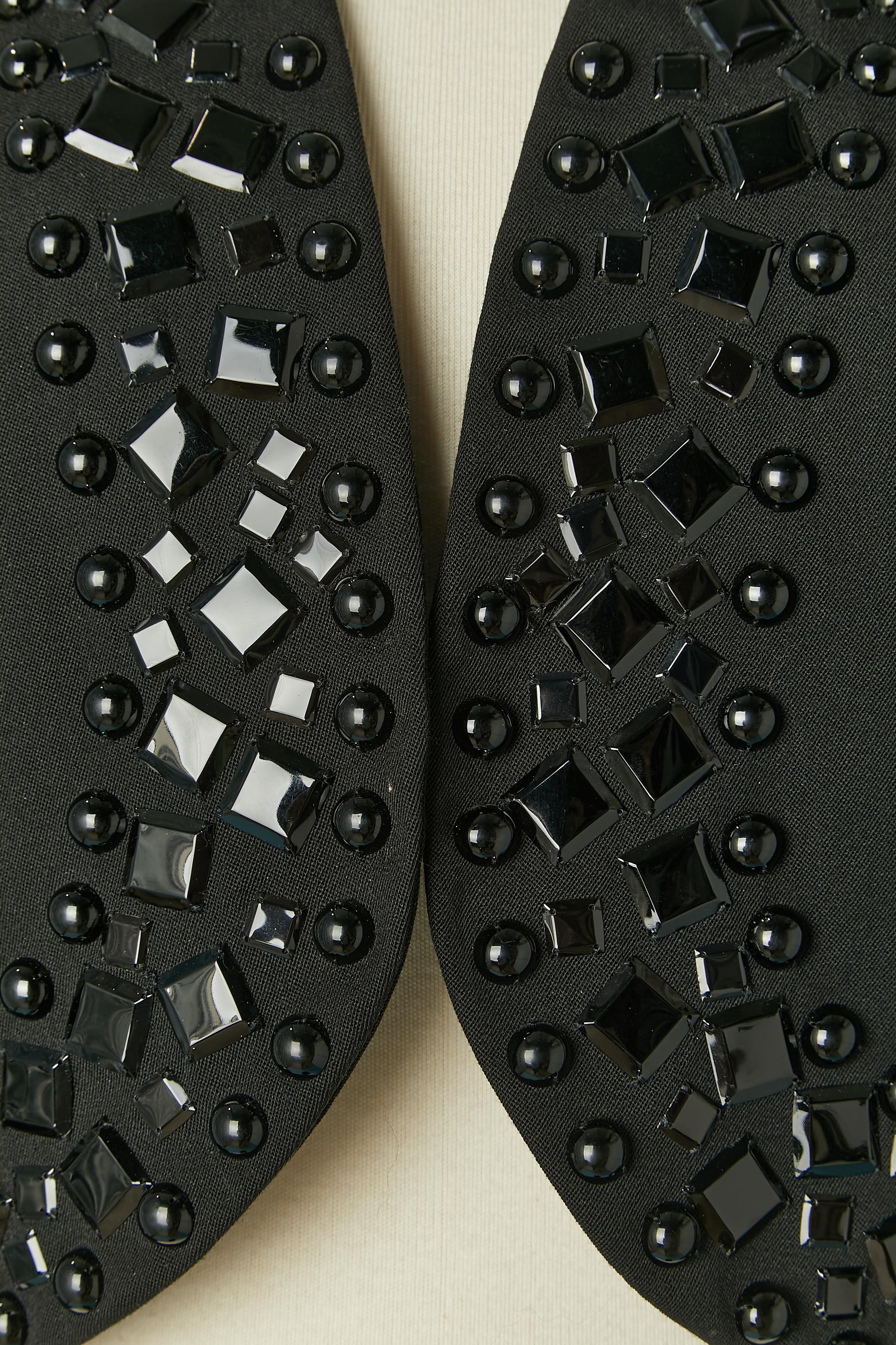 Schwarzer Boléro mit schwarzen Cabochons an der Kante. Kein Etikett für die Stoffzusammensetzung, aber der Hauptstoff ist wahrscheinlich Wolle und das Futter Acetat oder Viskose. 
Größe 44 (Fr) L 