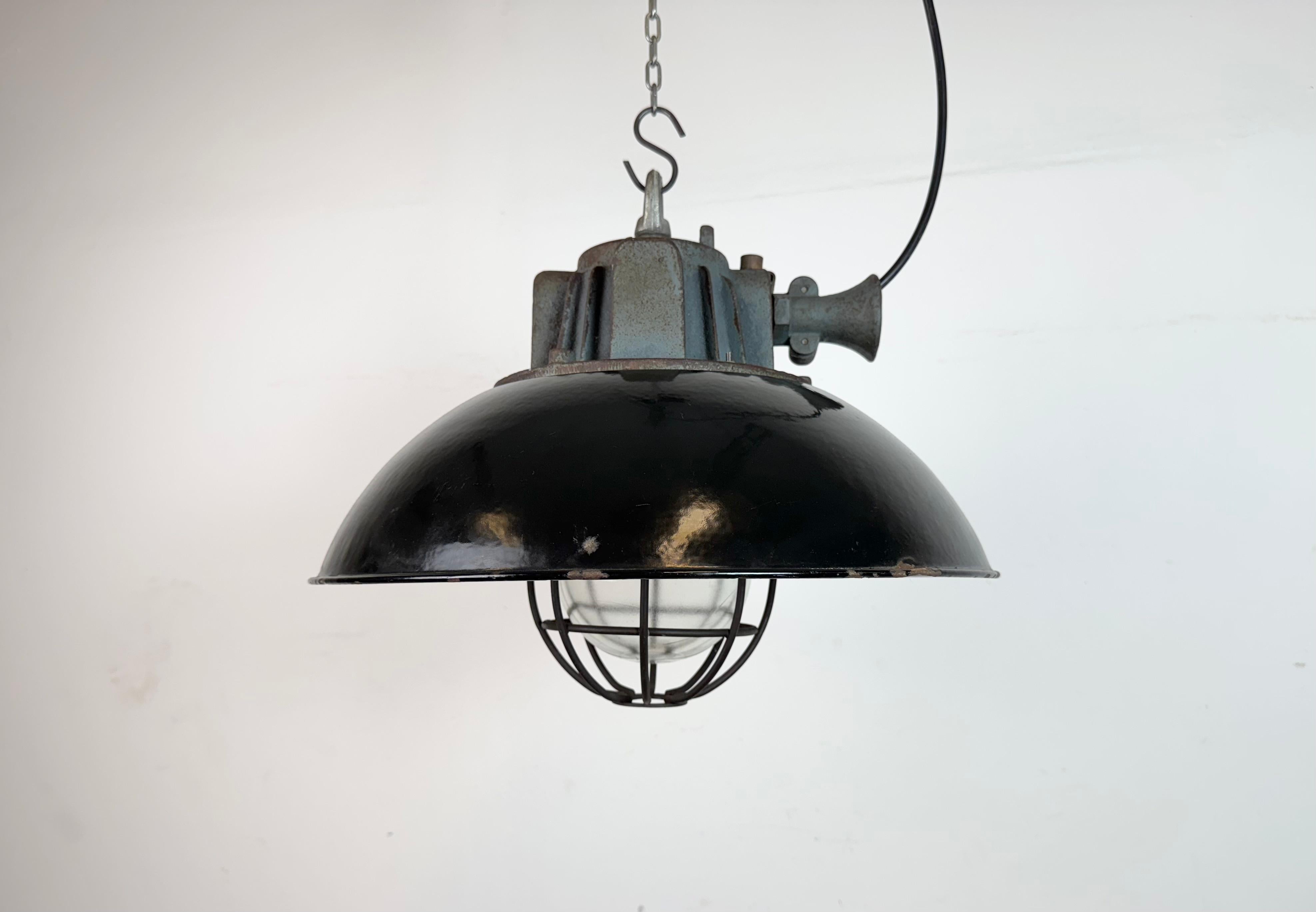Lampada a sospensione industriale prodotta da Elektrosvit nell'ex Cecoslovacchia negli anni Sessanta. Presenta un paralume in smalto nero, un interno in smalto bianco, un piano in ghisa, un coperchio in vetro trasparente e una griglia in