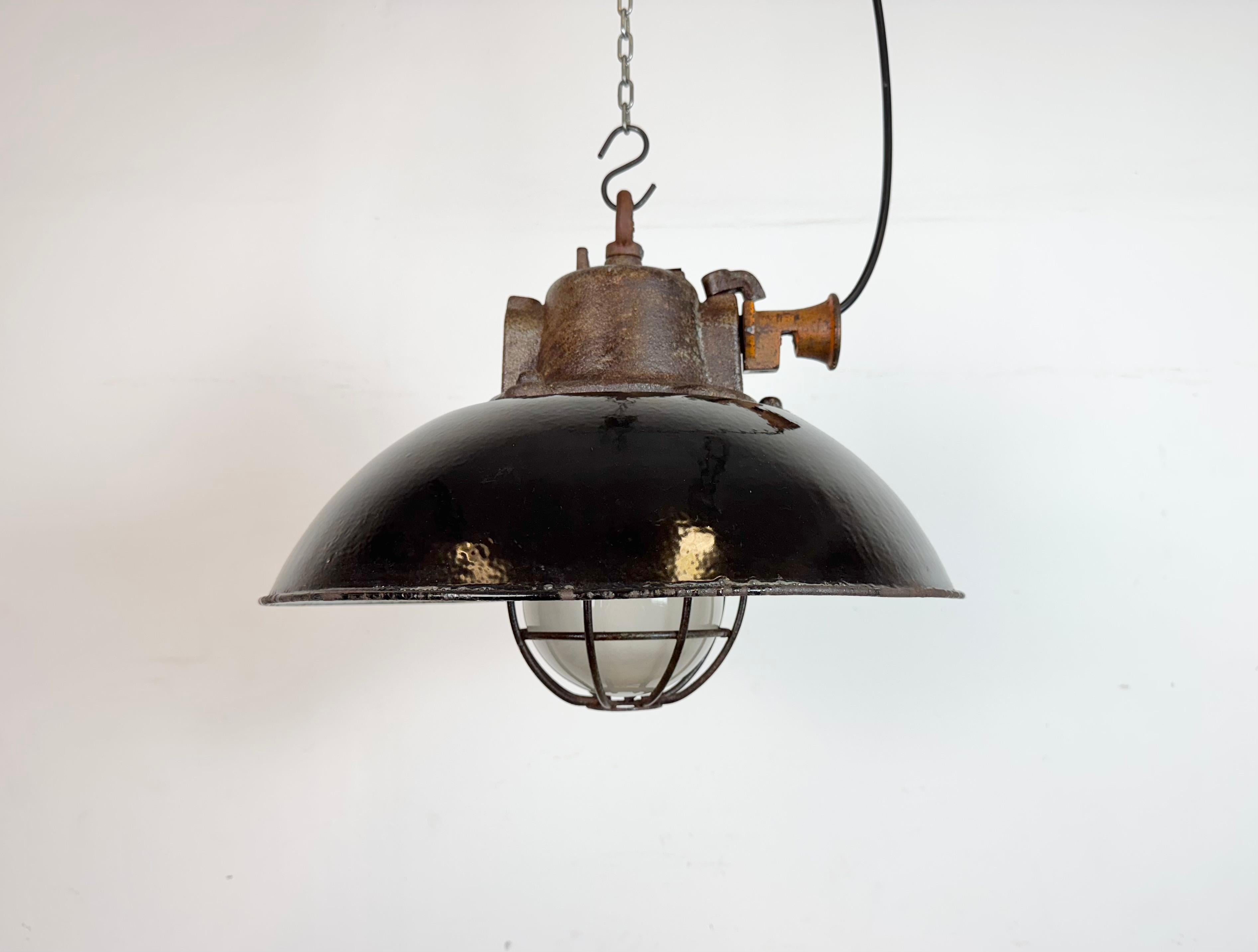 Lampada a sospensione industriale prodotta da Elektrosvit nell'ex Cecoslovacchia negli anni Sessanta. Presenta un paralume in smalto nero, un interno in smalto bianco, un piano in ghisa, un coperchio in vetro trasparente e una griglia in