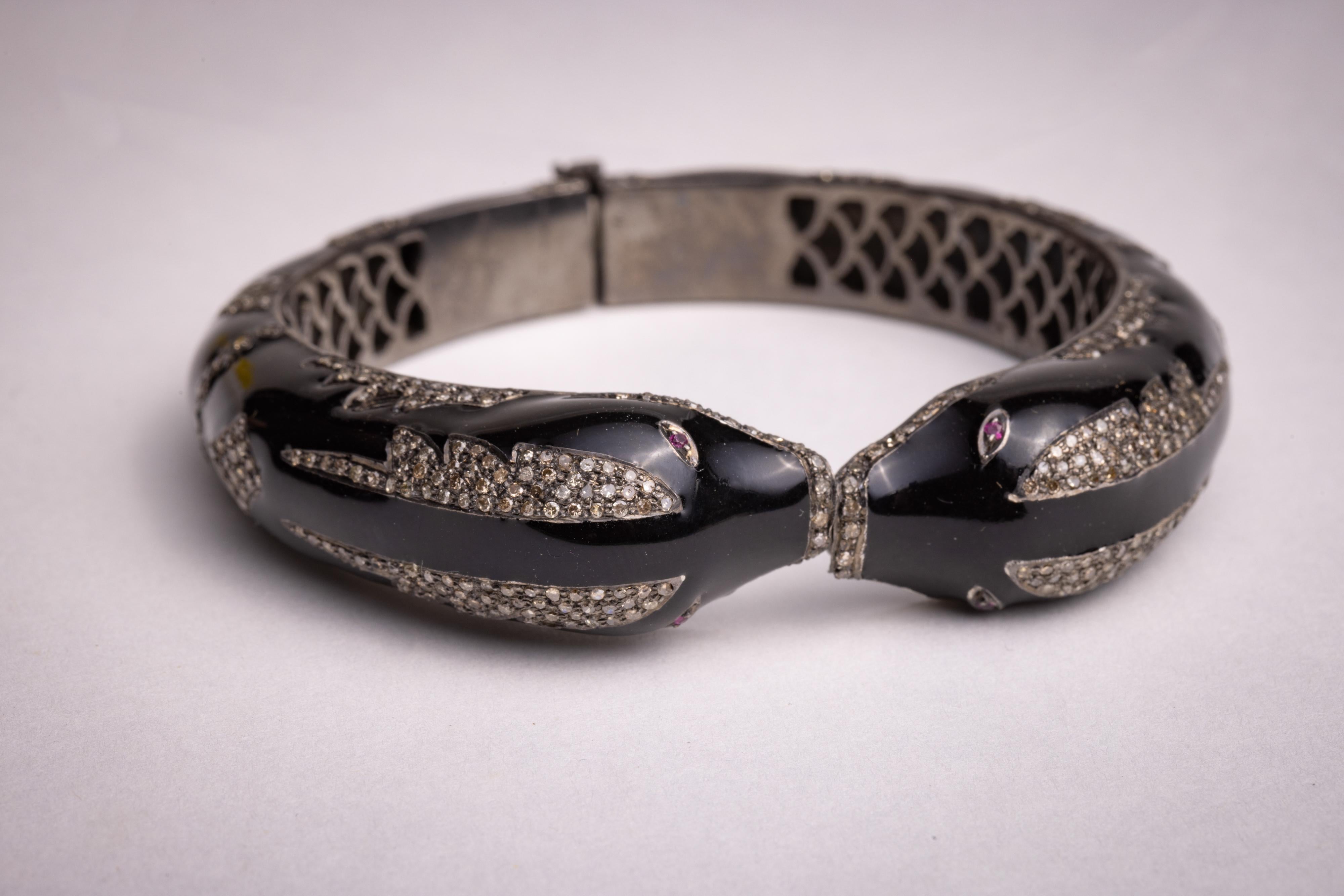 An unusual and extraordinary cuff snake bracelet.  Black enamel with round, brilliant cut diamonds in a pave` setting. Faceted ruby eyes.  Hinged back for easy on and off.  A slight oval shape keeps the snake heads lying on top of the wrist.  Inside
