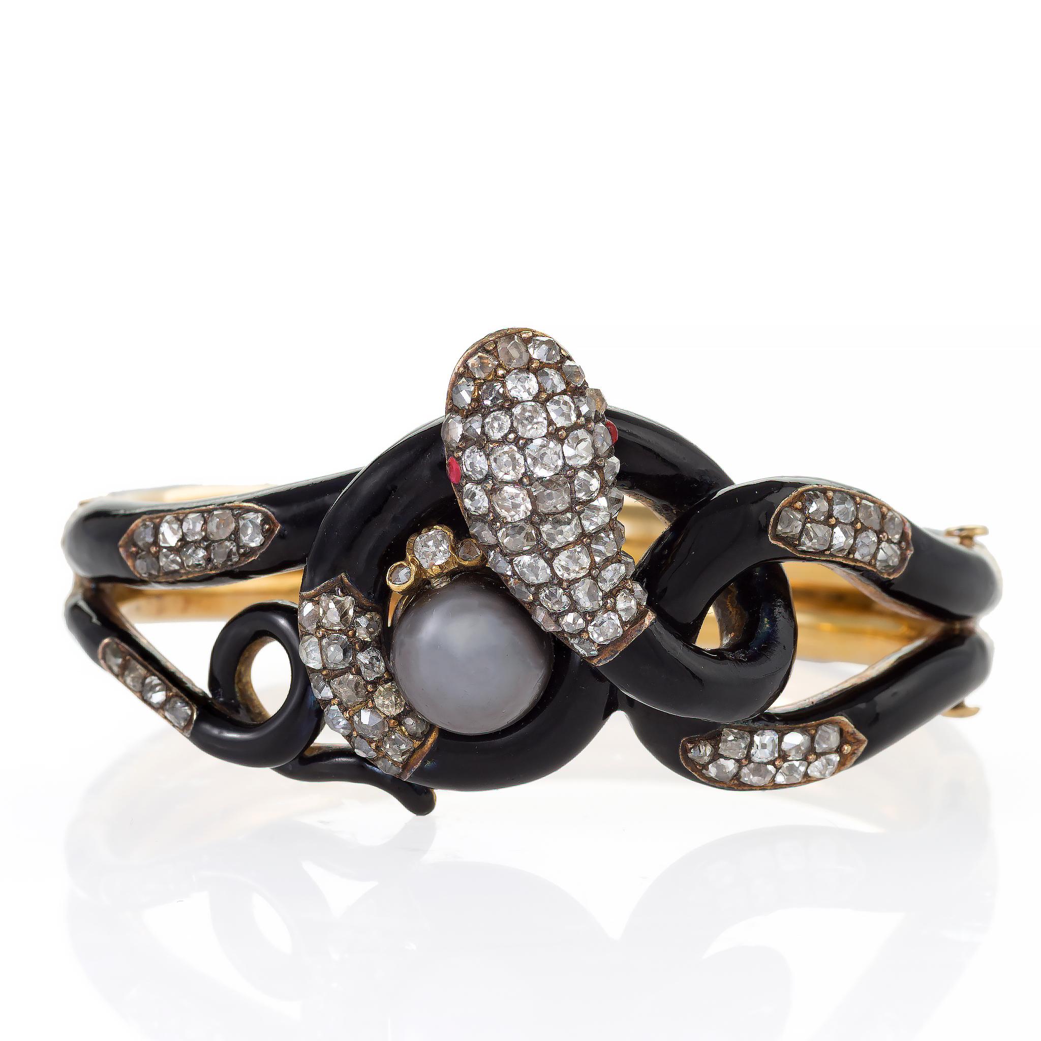 Dating from the mid-19th century, this antique French serpent bangle bracelet is composed of black enamel, natural gray pearl, diamonds, and rubies. It is designed as a highly three-dimensional black enamel snake with ruby eyes, its body patterned