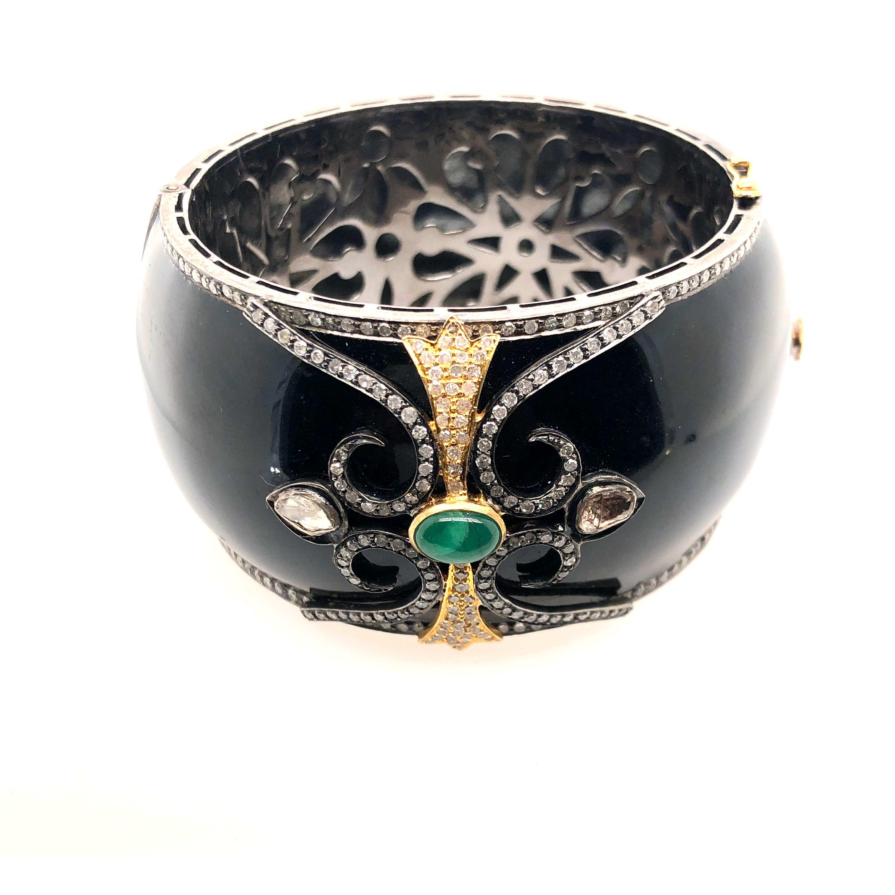 Designer black enamel bangle with diamond motif on top and around. This bangle is openable and has beautiful floral silver grill inside for smooth feel inside.

Closure: Box Clasp

14k: 5.74gms
Diamond: 5.1ct
Silver: 92.4gm
Emerald: 1.5ct