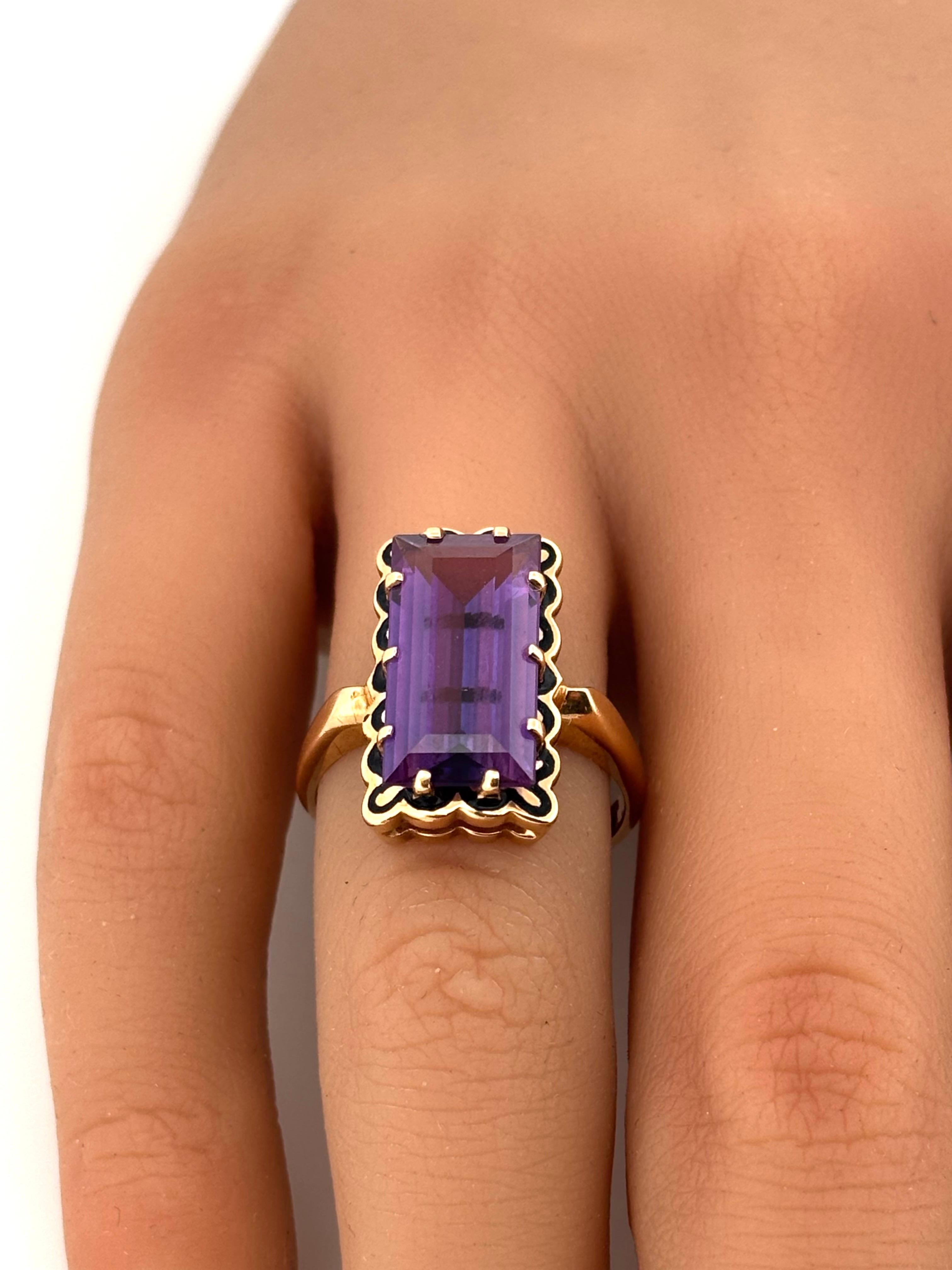 Dieser auffällige Ring aus schwarzer Emaille und Amethyst präsentiert eine kühne, vom Vintage-Stil inspirierte Eleganz in 14 Karat Gelbgold. In seinem Zentrum ruht ein purpurfarbener Amethyst im Smaragdschliff, der eine beeindruckende Länge von