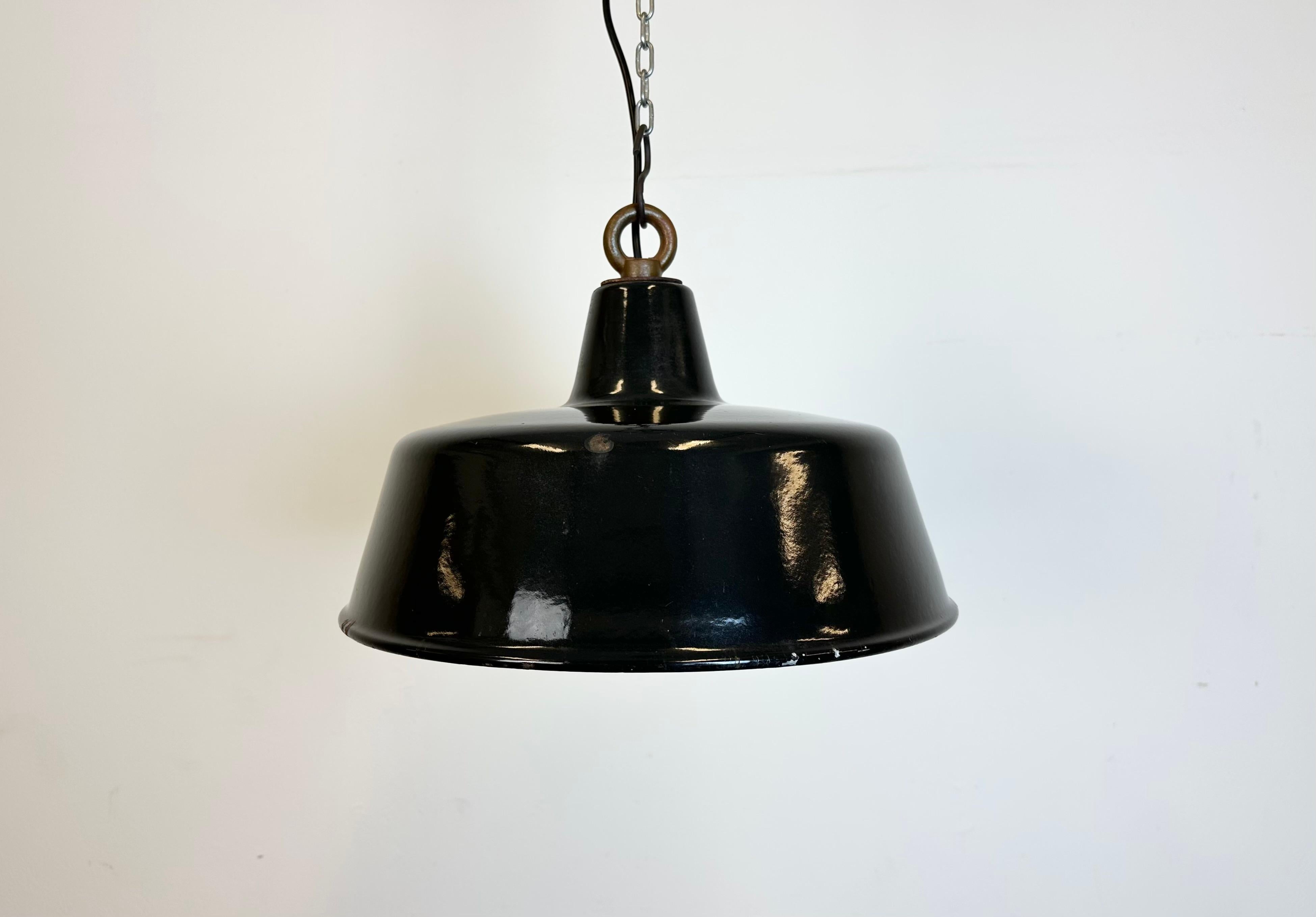 Industrial black enamel pendant lamp with white interior. Iron top. Manufactured during the 1950s. New porcelain socket rerquires standard E 27/ E26 light bulbs. New wire The diameter of the shade is 35 cm. The weight of the lamp is 1,4 kg.