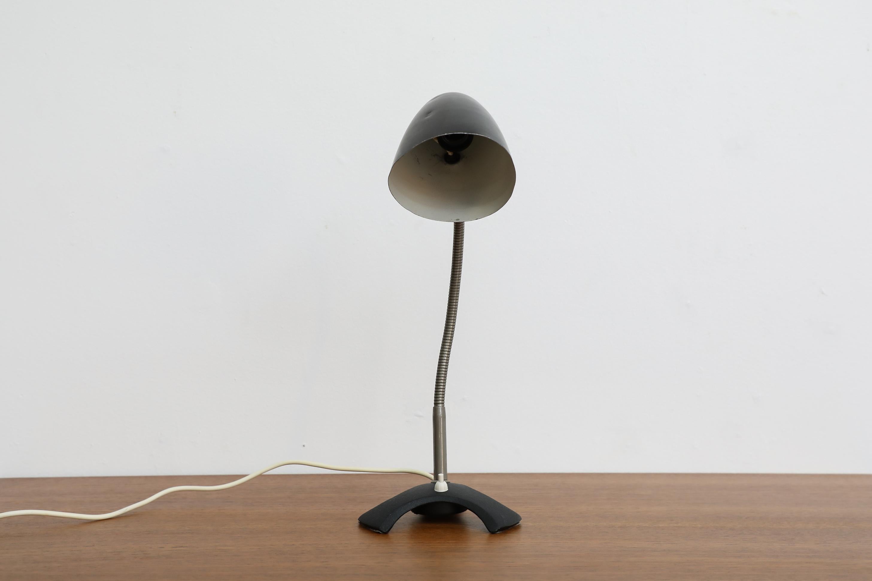Mid-Century, Bauhaus style, goose neck desk lamp with black enameled shade and metal base. Adjustable in all directions. In original condition with visible wear, including scratches. Wear is consistent with its age and