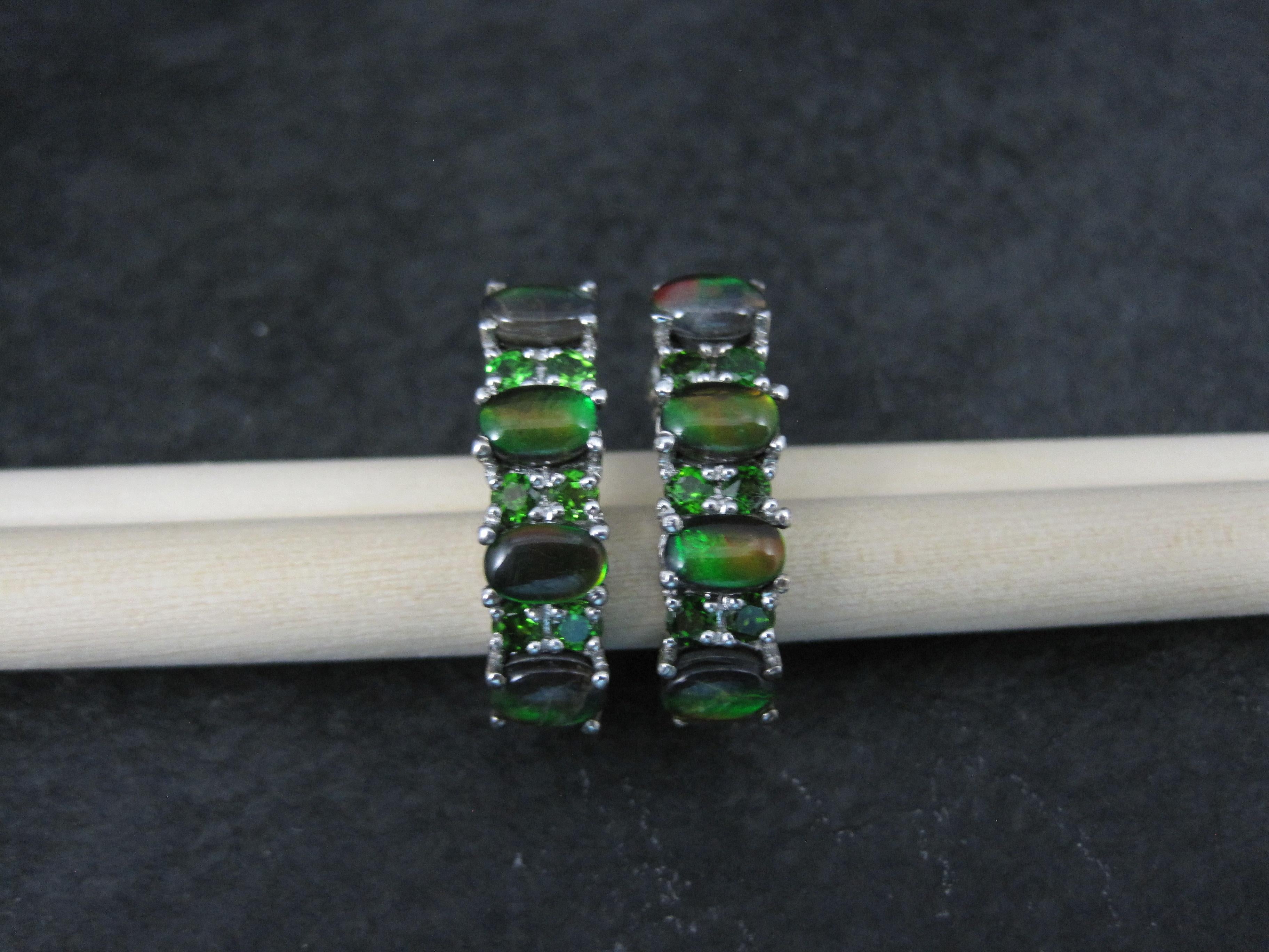 These gorgeous earrings are sterling silver.
They feature 8 oval 4x6mm black Ethiopian opals accented by 12 round 3mm chrome diopside gemstones.

The earrings measure 1/4 by 1 inch,
Weight: 5.8 grams

Marks: 925

New old stock

