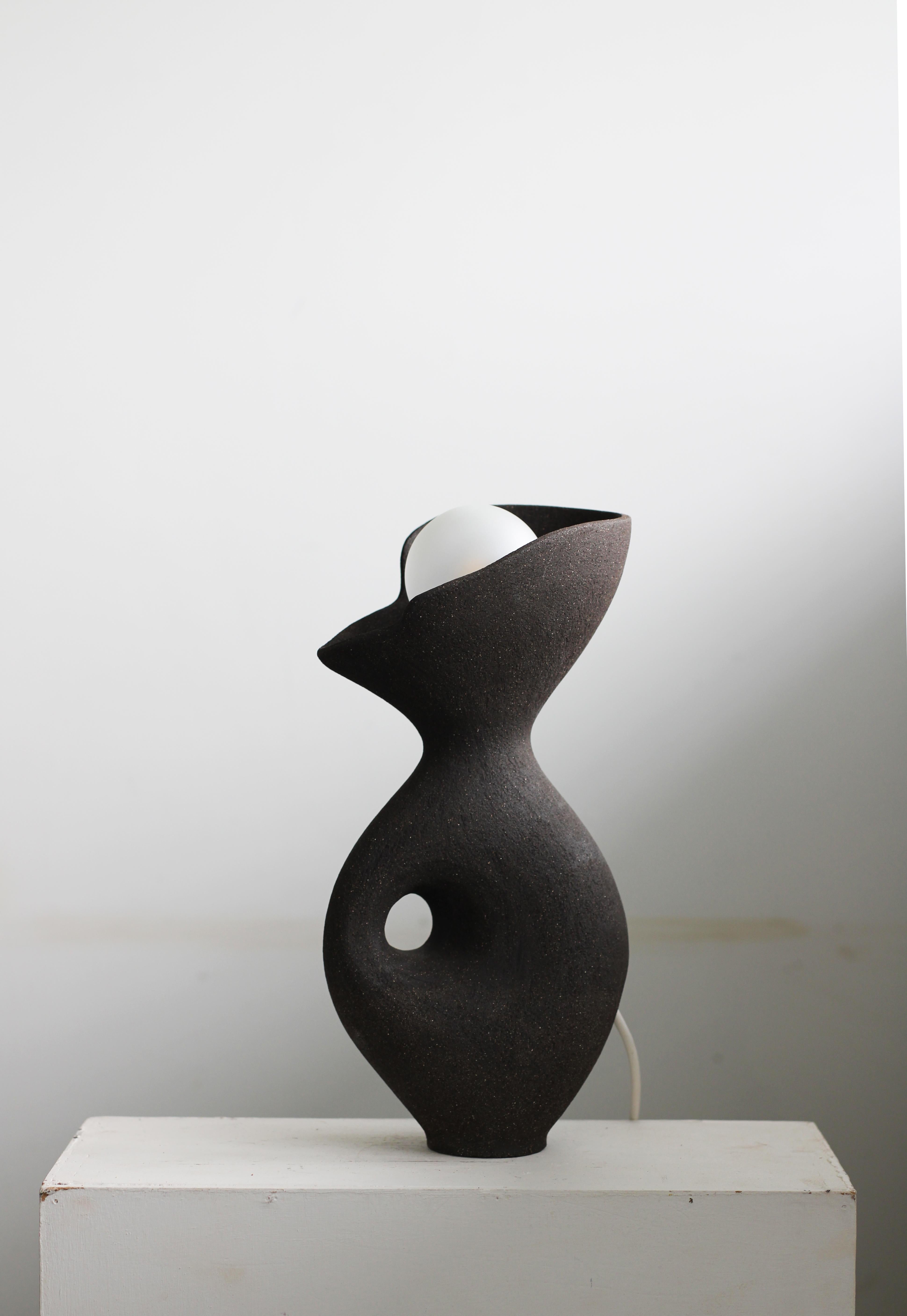 Lampe Exo noire d'Abraham Javed
Dimensions : L 20 x 32 H cm (Les dimensions sont variables)
MATERIAL : Céramique en grès, laiton.
Plusieurs options de couleurs et de tailles pour l'argile.

Forme creuse enroulée avec une surface en céramique non
