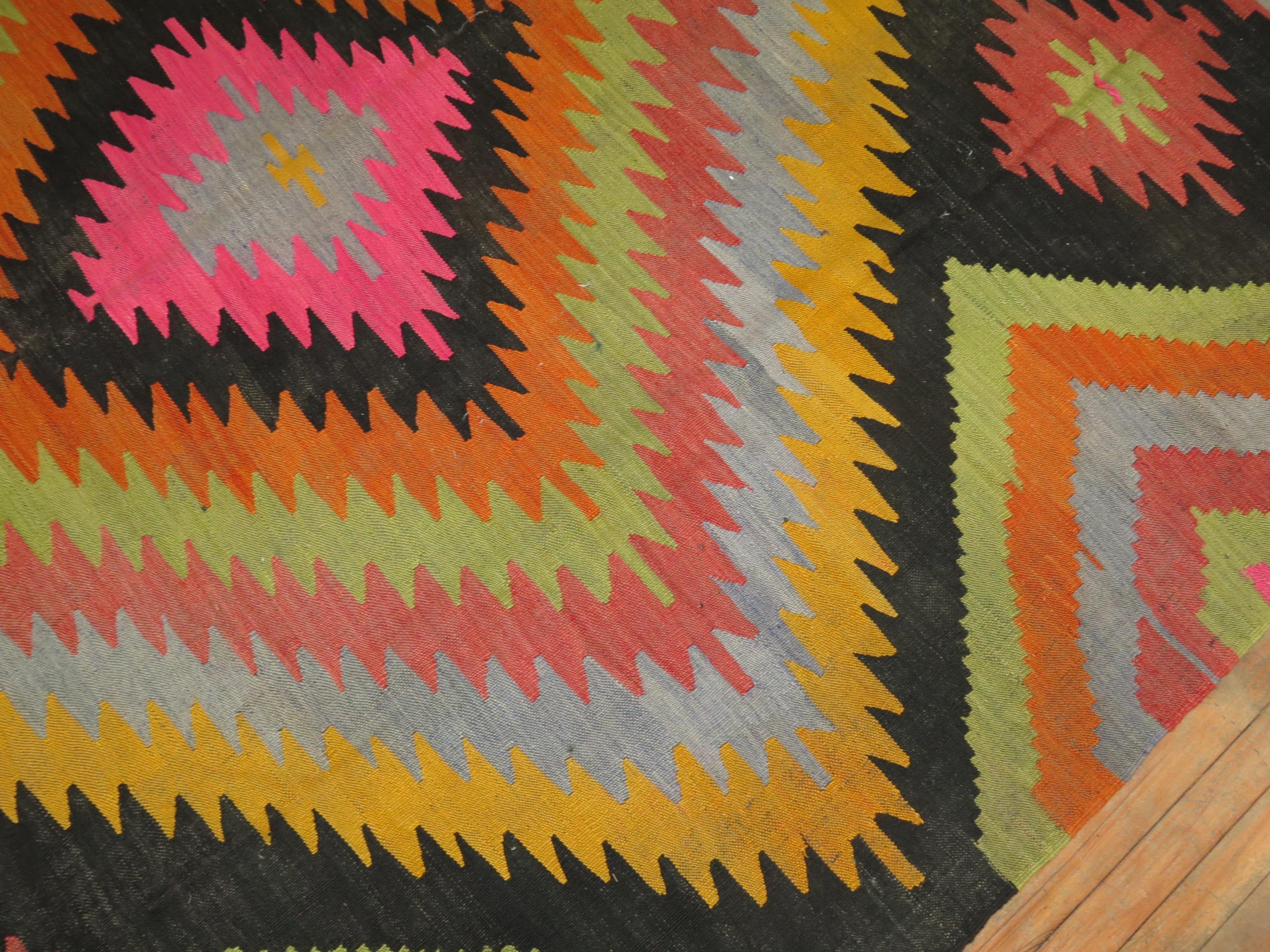 A dazzling midcentury room size Turkish Kilim flat-weave. Large scale design with intense colors on black field. A piece for the boho chic home

Measures: 8'2” x 10'10”.