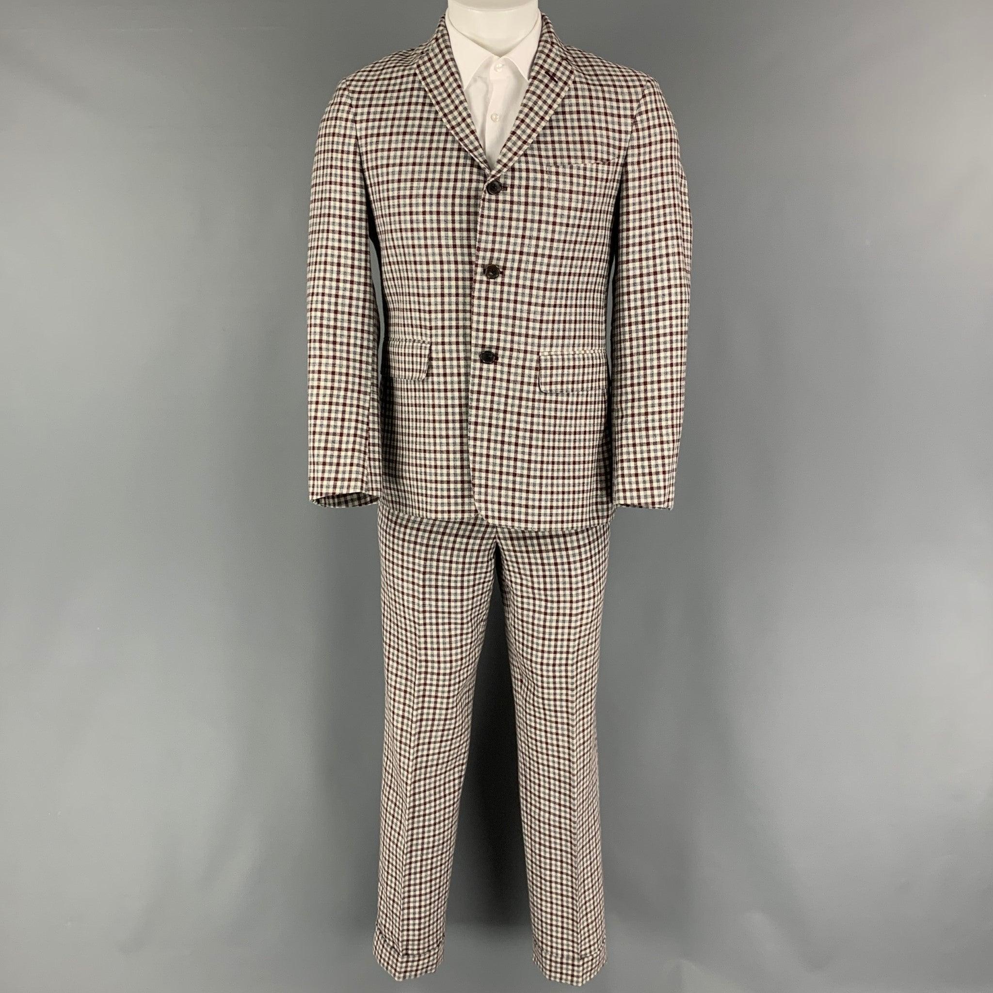 BLACK FLEECE suit comes in a burgundy, cream and grey checkered wool blend woven with a full liner and includes a single breasted, three button sport coat with a notch lapel and matching flat front trousers. Made in USA.Very Good Pre-Owned