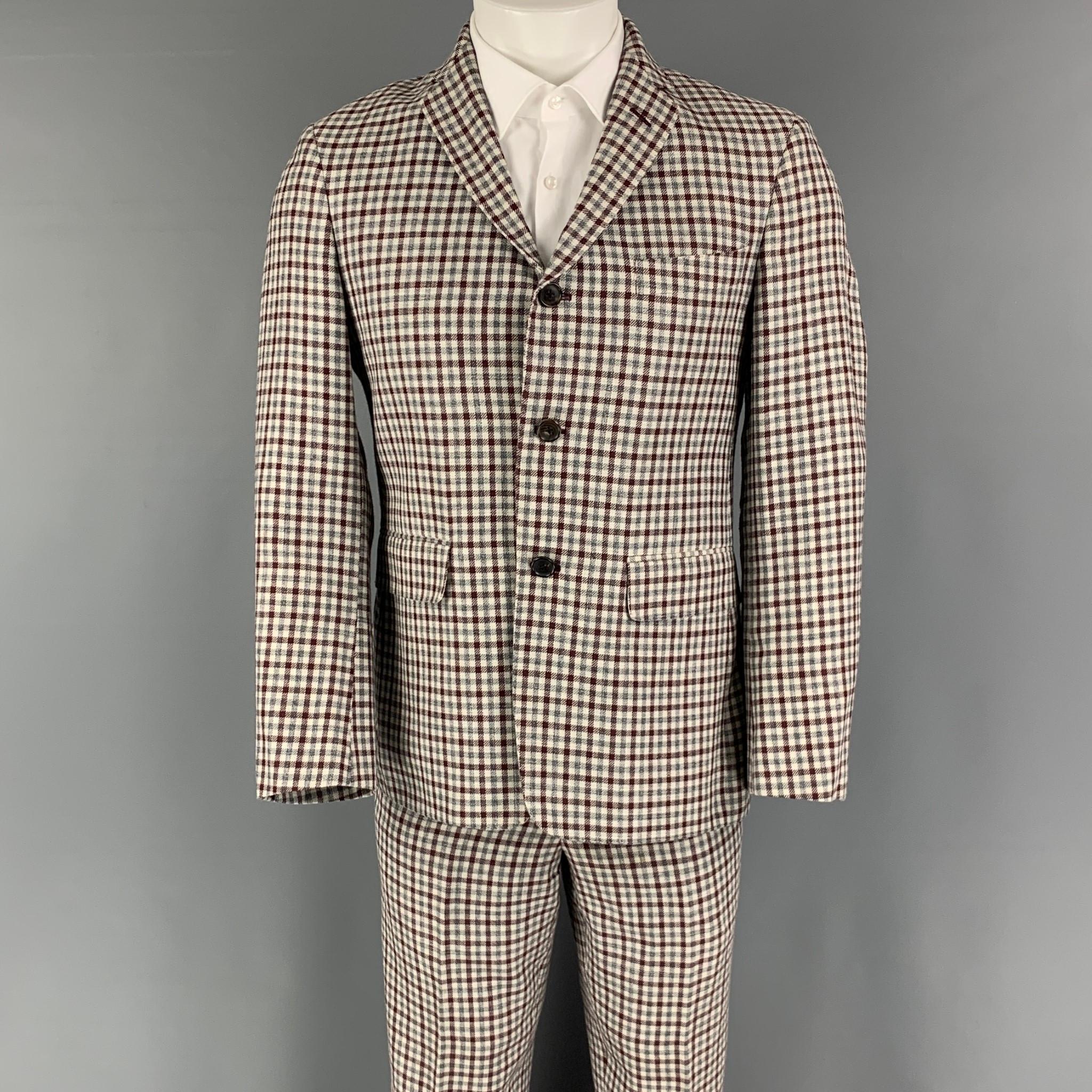 BLACK FLEECE suit comes in a burgundy, cream and grey checkered wool blend woven with a full liner and includes a single breasted, three button sport coat with a notch lapel and matching flat front trousers. Made in USA.

Very Good Pre-Owned