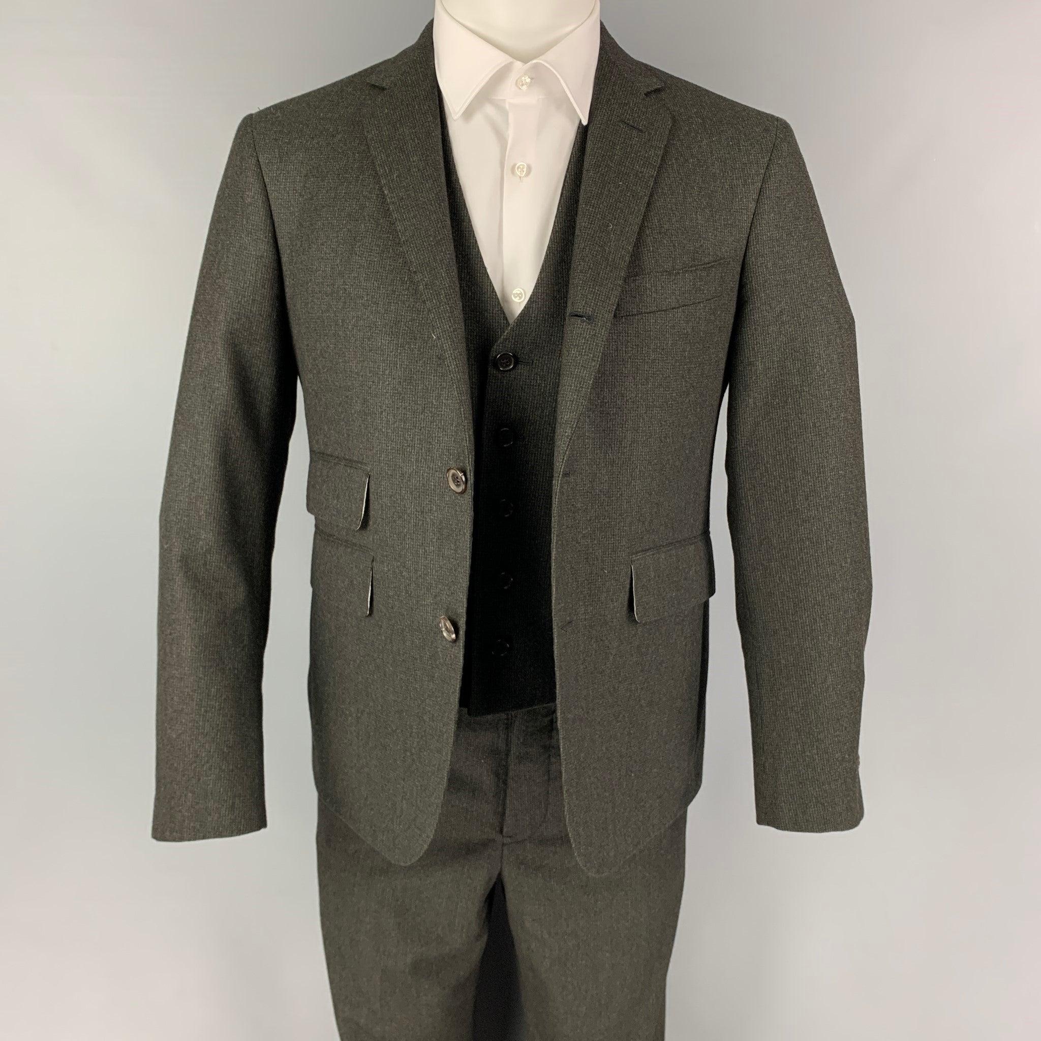 BLACK FLEECE
3 Piece suit comes in a grey & charcoal grid print wool and includes a single breasted, double button sport coat with notch lapel and a matching vest & flat front trousers. Very Good Pre-Owned Condition. Light discoloration at interior.