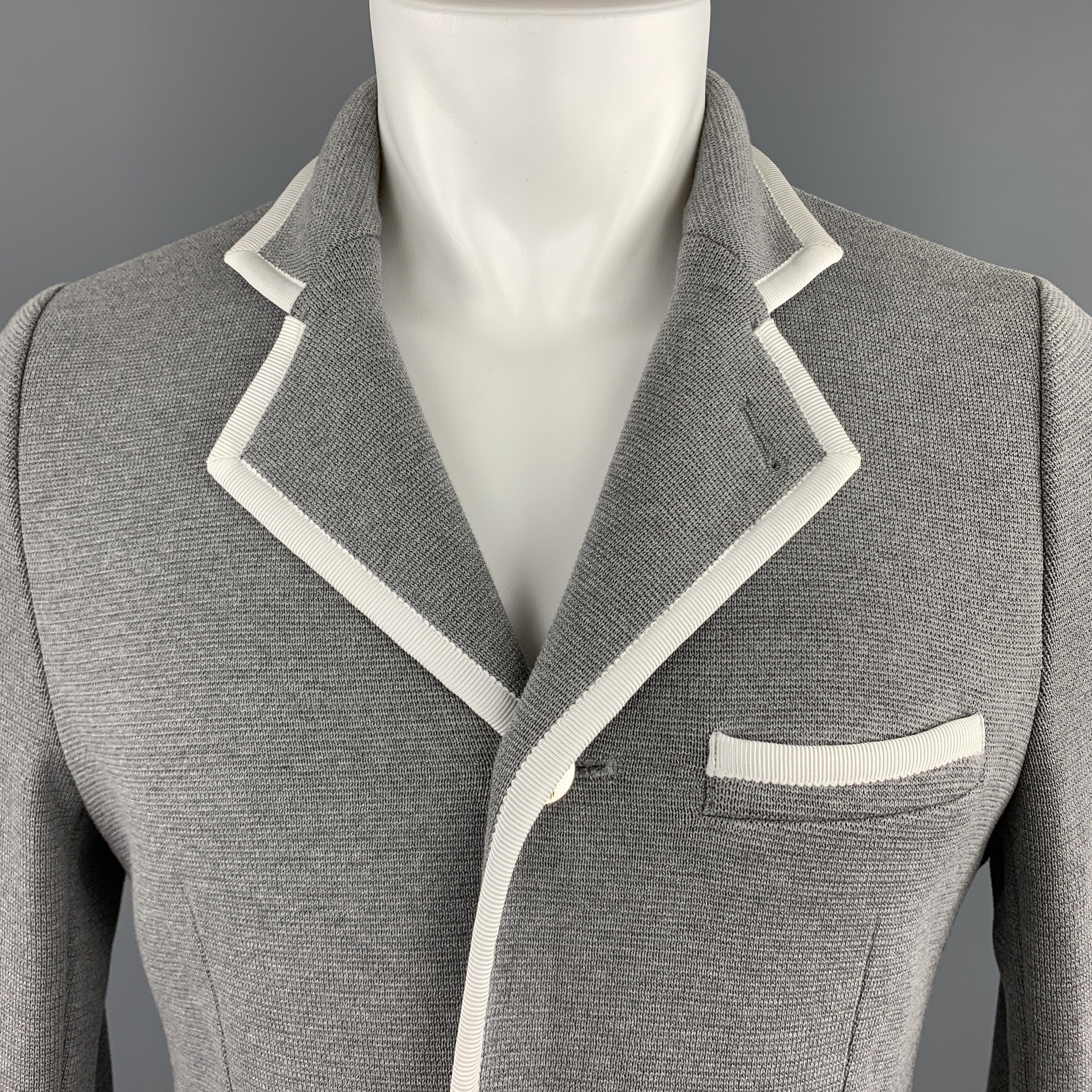 BLACK FLEECE sport coat comes in grey cotton knit with a notch lapel, single breasted, three silver tone metal button front, and cream faille contrast piping throughout. Label removed. As is. 

Excellent Pre-Owned Condition.
Marked: (no