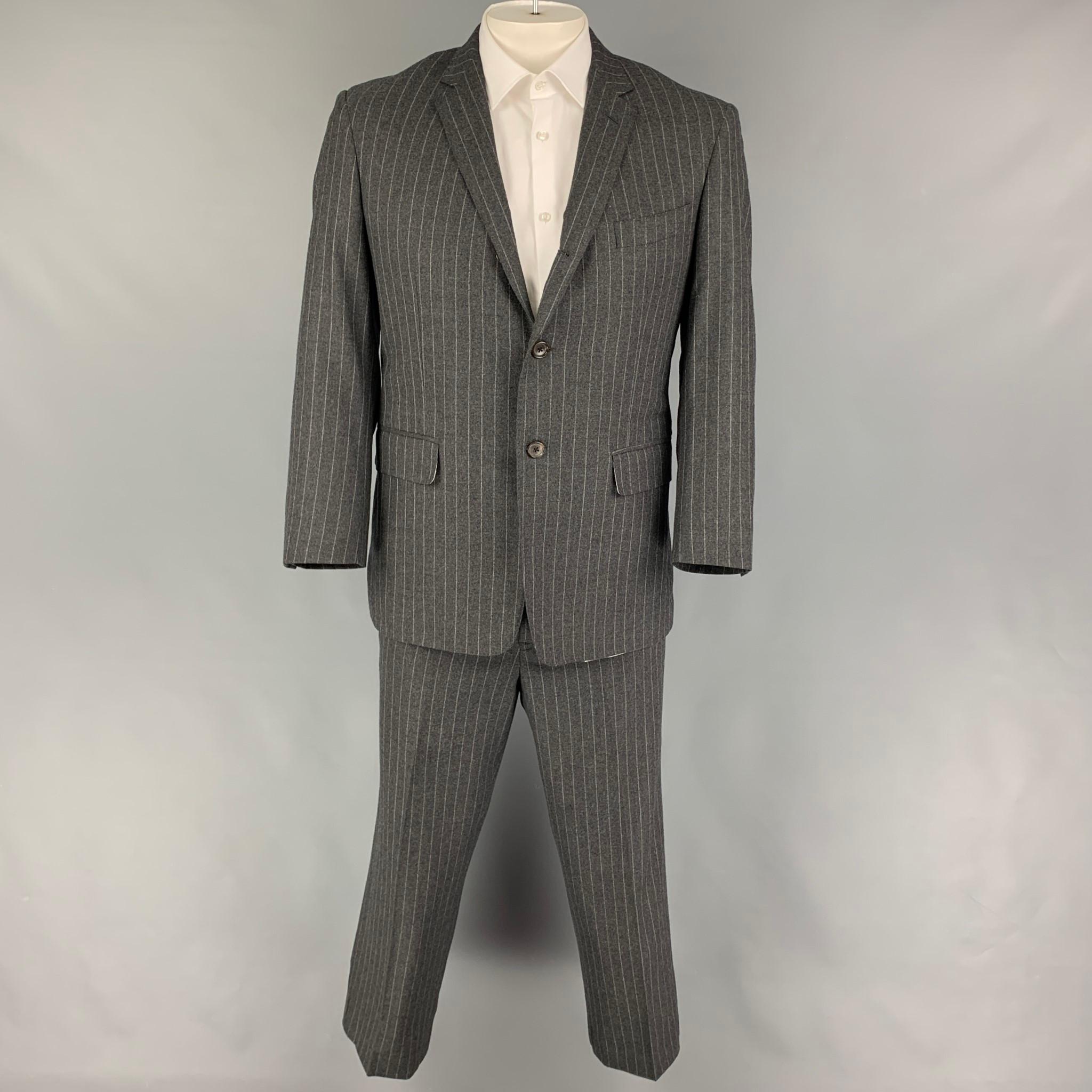 BLACK FLEECE suit comes in a dark gray stripe wool and includes a single breasted, three button sport coat with a notch lapel and matching flat front trousers. Made in USA.

Very Good Pre-Owned Condition.
Marked: 42

Measurements:

-Jacket
Shoulder: