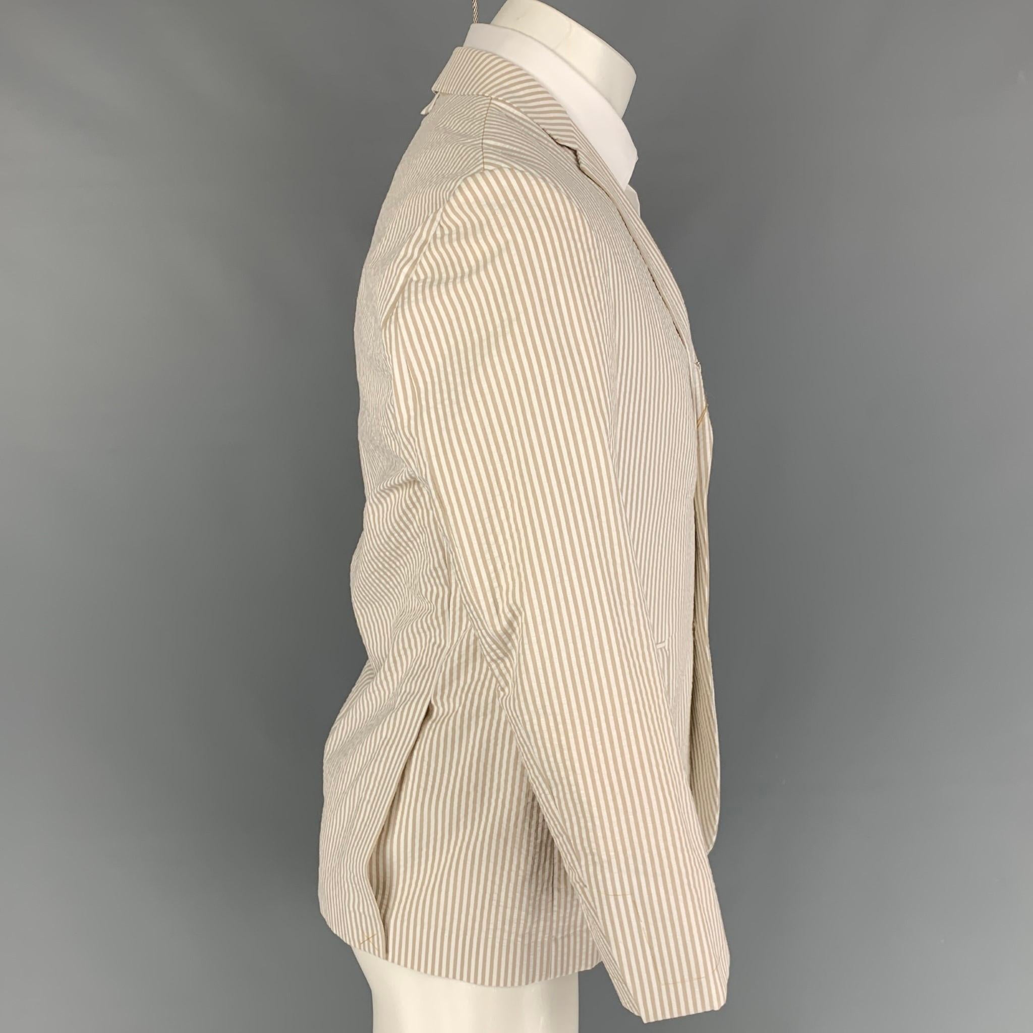 BLACK FLEECE sport coat comes in a taupe & white stripe cotton featuring a half liner featuring a notch lapel, flap pockets, double back vent, and a three button closure. Comes with tags. 

Very Good Pre-Owned Condition. Light discoloration at