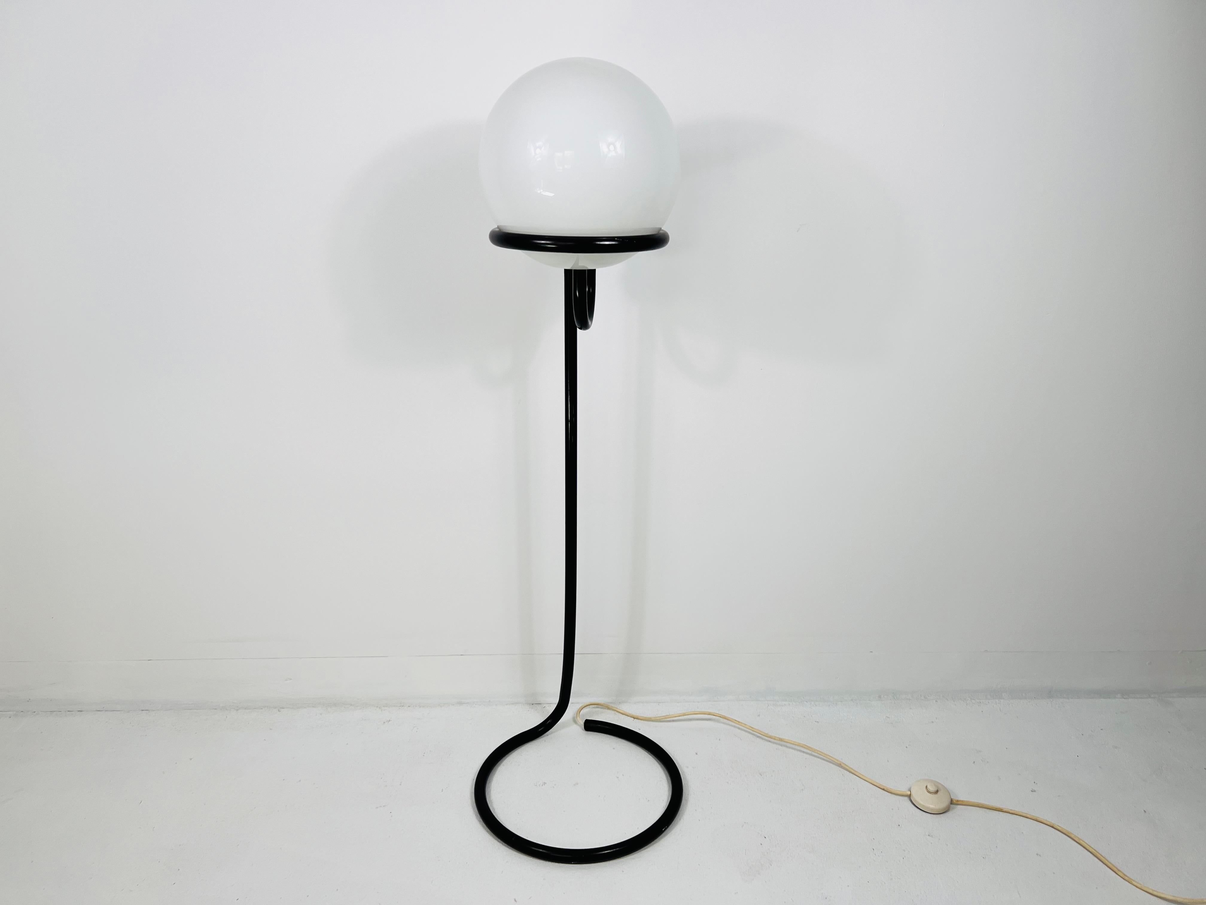 This striking floor lamp, designed by Aldo van den Nieuwelaar for Domani Designs, Amsterdam, is a quintessential piece of mid-century modern design from the 1960s. Featuring a sleek black metal stand and a white opal glass globe, the lamp presents a