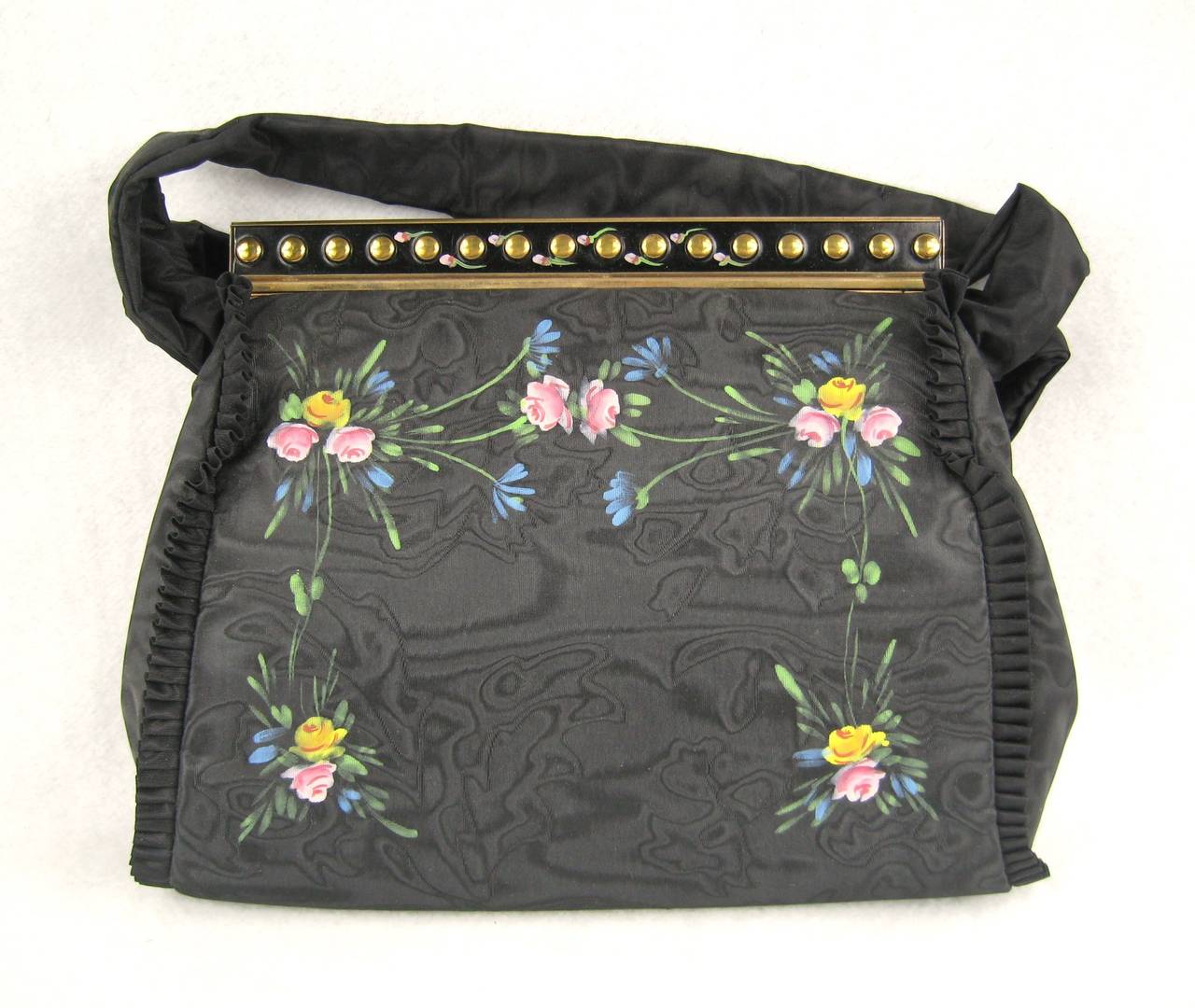 Stunning! In its original box this black floral hand-painted handbag is Stunning! It has all the items found in a handbag from this era still in it, wrapped up and never used. The bag measures 10 inches across bottom x 8 inches high. With strap, it