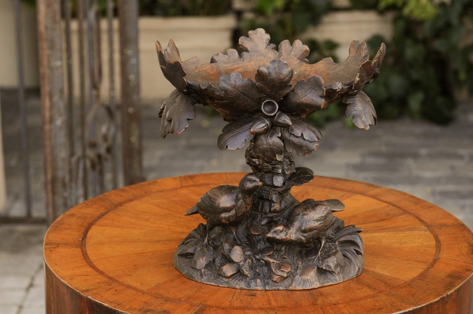 A Swiss Black Forest compote from the late 19th century, with hand carved birds and foliage. Born in Switzerland in the later years of the 19th century, this charming wooden compote features a luscious tree, supporting an upper bowl made of oak