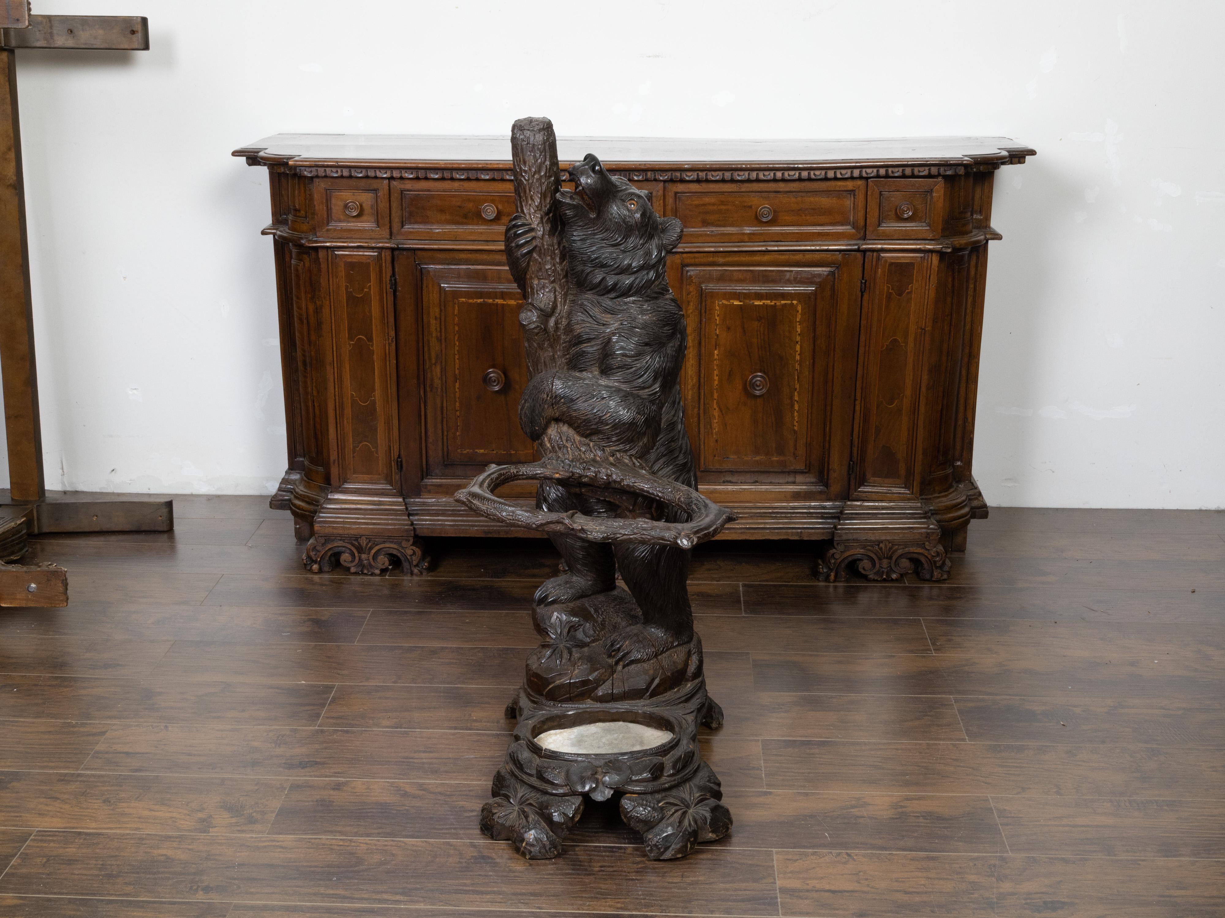 A large Black Forest carved wooden umbrella stand from the late 19th century, depicting a bear climbing a tree branch. Created during the last decade of the 19th century, this Black Forest umbrella stand features a large bear, firmly planted on his