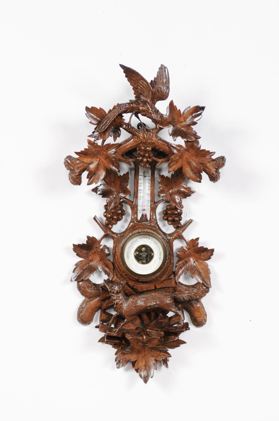 A Black Forest aneroid barometer and thermometer from the first half of the 20th century, with foliage, bird and fox. This exquisite Black Forest barometer features a beautifully hand carved frame, presenting lucious foliage and branches on which a