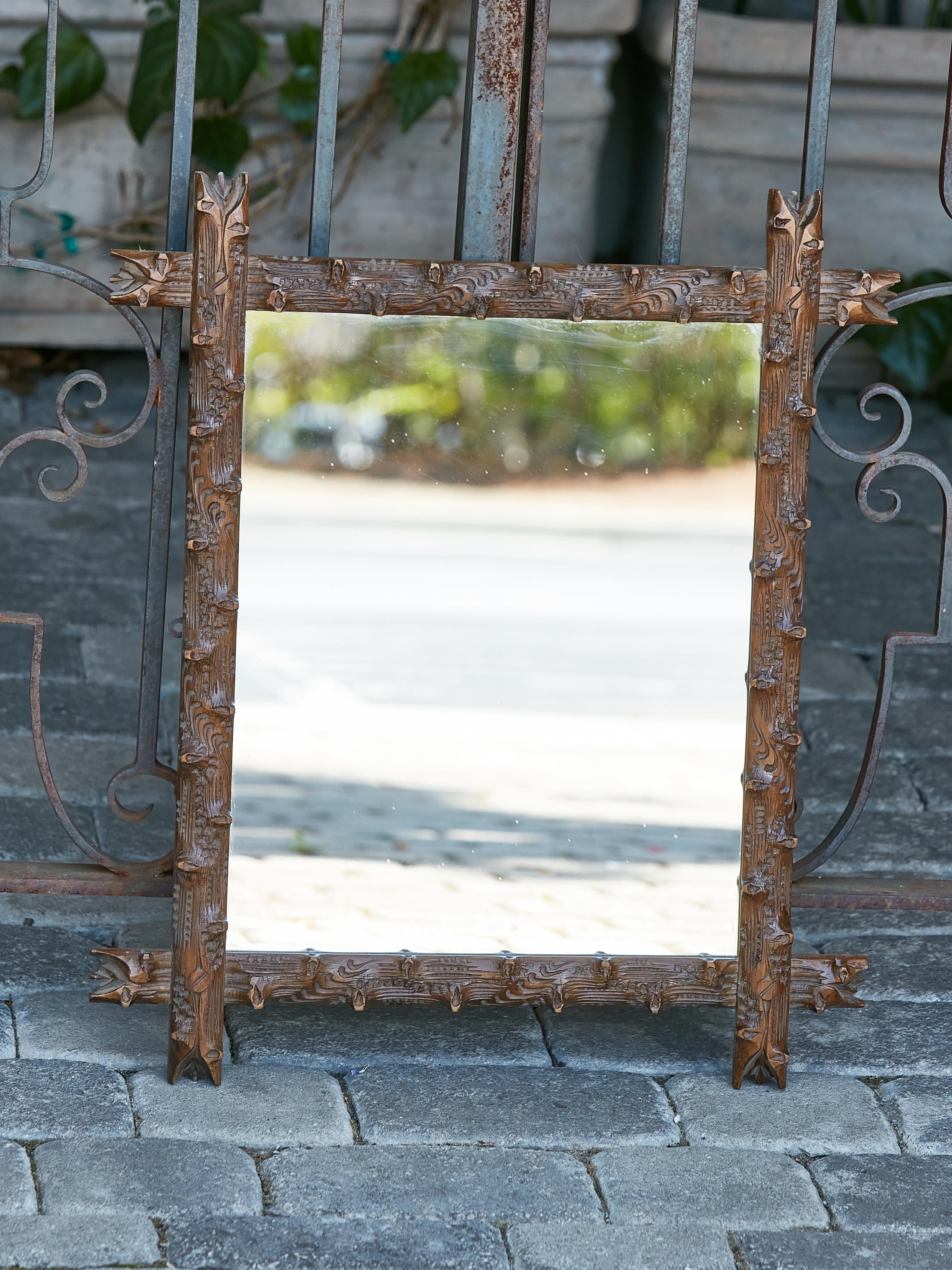 A Black Forest wooden mirror from the 19th century with hand-carved wooden frame inspired by tree branches. This charming 19th-century Black Forest wooden mirror is akin to a window into a sylvan fairy tale. With a frame masterfully hand-carved to