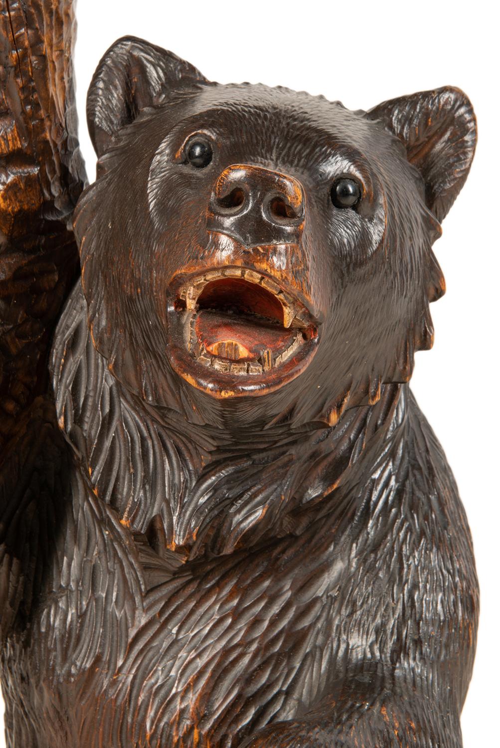 An amusing late 19th century Black Forest carved wood bear side table, originally intended as a smoking compendium. Having two small bears lying on their back as lids to two compartment, carved tree and leaf like decoration to the top, with two