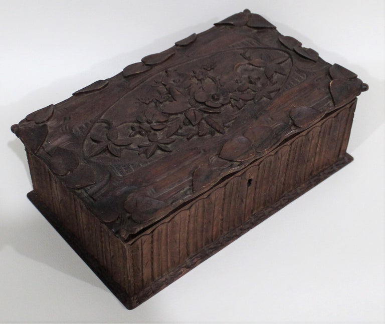 Dark walnut Black Forest hand carved box with floral spray to top.