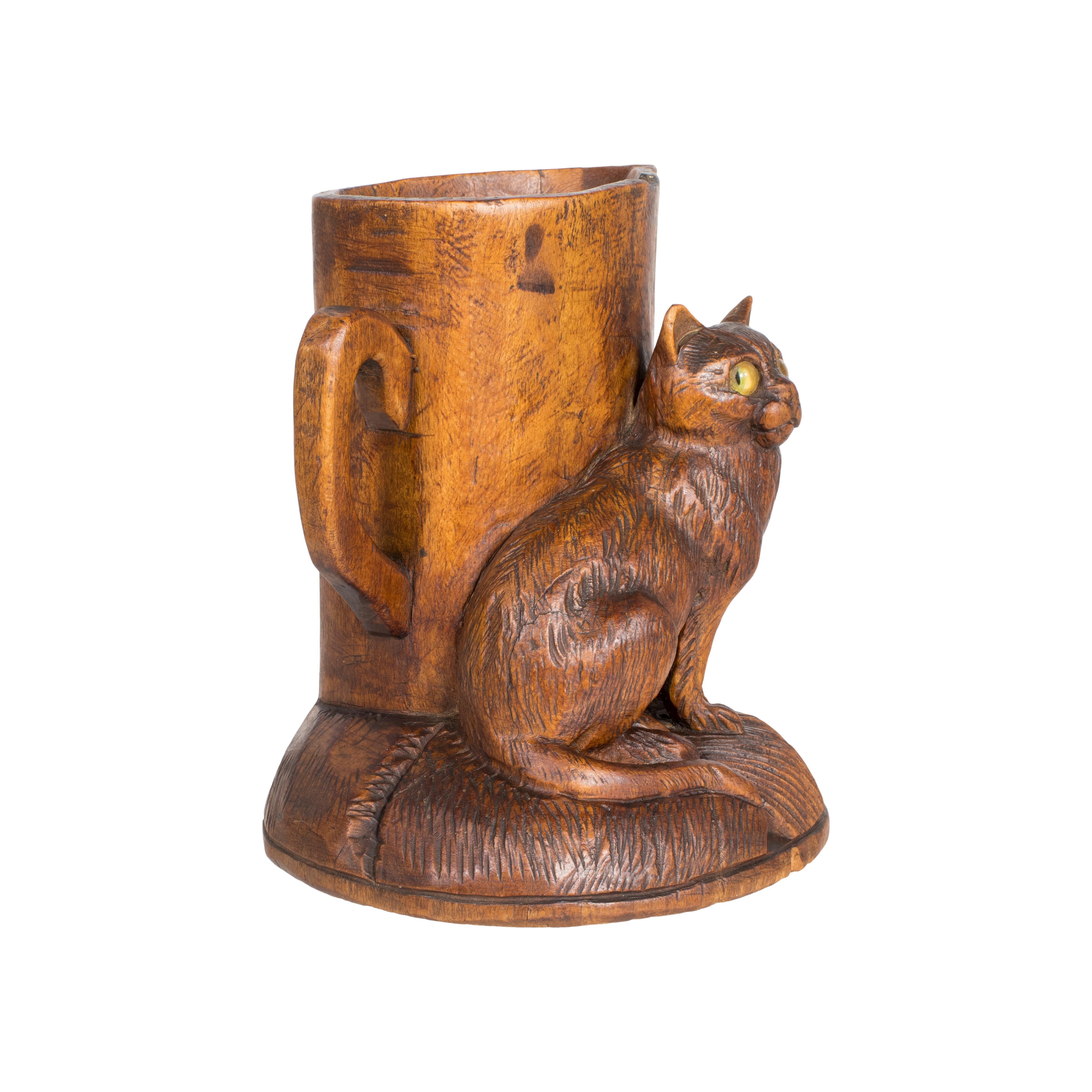Swiss carved match holder with a cat with glass eyes seated beside a pitcher. In the 1800’s the wood carving industry of Switzerland started in the town of Brienz. By the end of the 1800’s it had become the driving force for this industry. Swiss