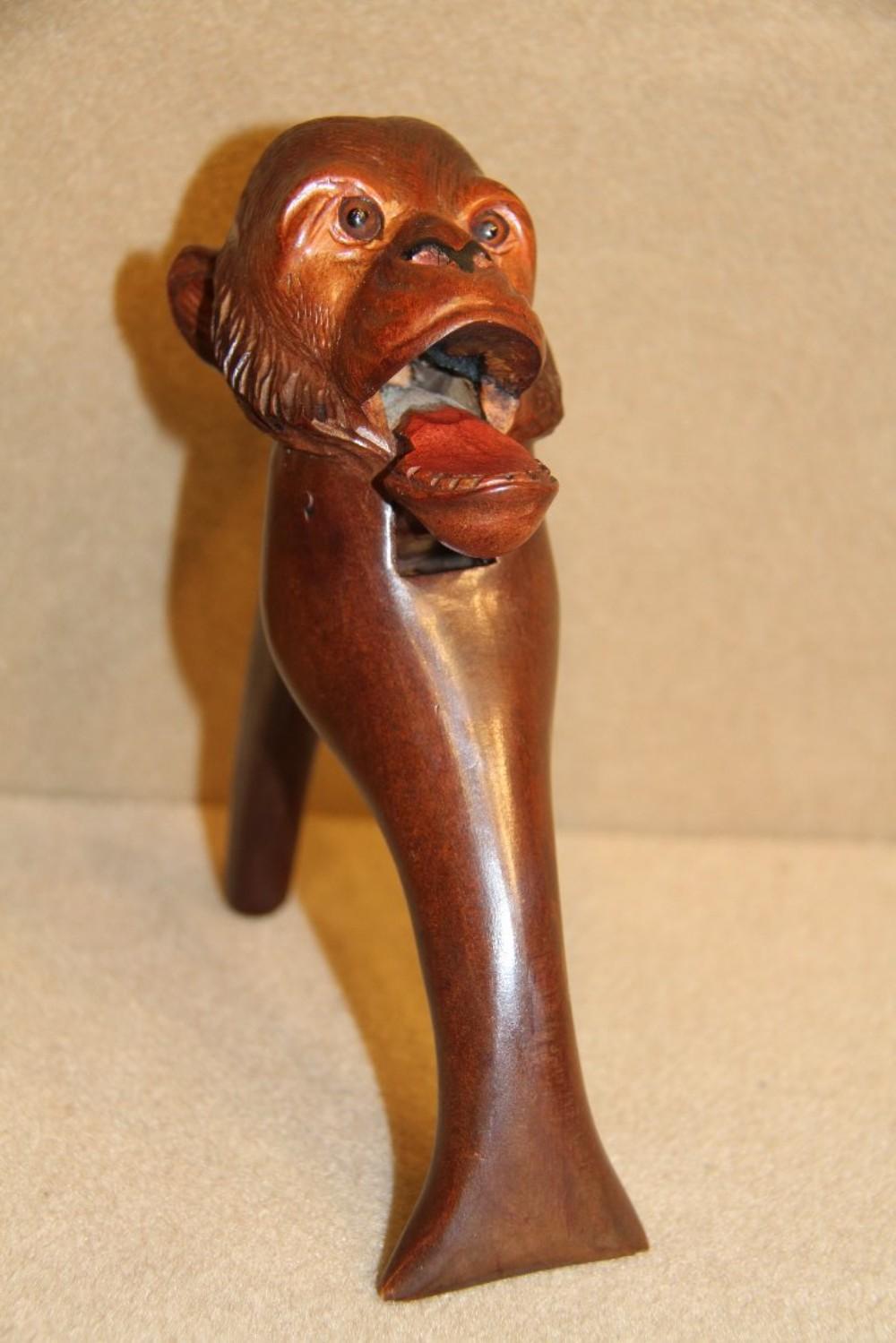 An amusing late 19th century novelty Black Forest carved walnut nut cracker in the form of a chimpanzee with original glass eyes. In good condition.