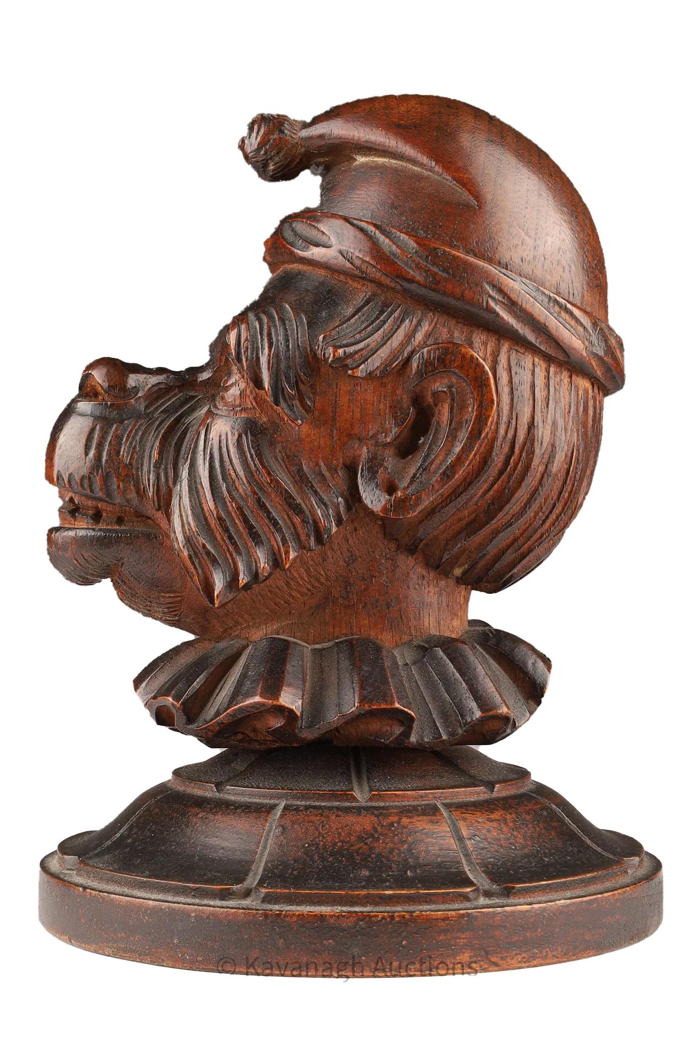 Black Forest figural carved wood humidor in the form of a monkey's head with a hinged lid carved as a hat, around the neck is a ruffled collar above a circular base with carved detail.