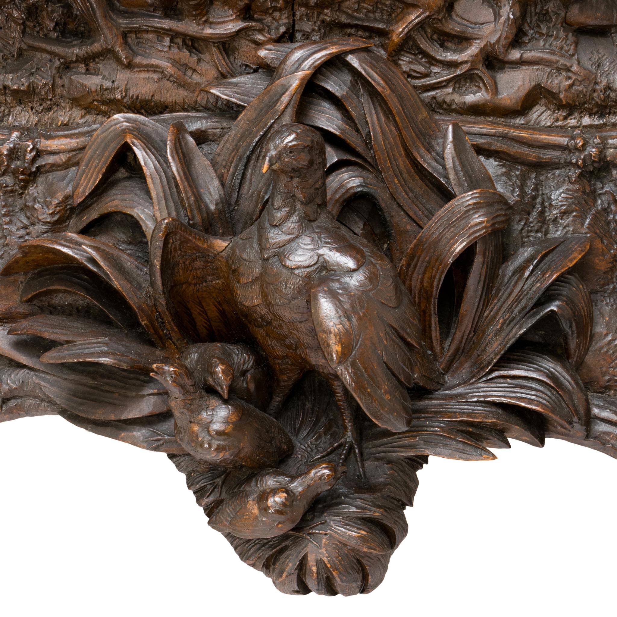 Horloge de jeu Black Forest sculptée en Suisse. Cette pièce exceptionnelle est ornée d'un cerf daim et d'une biche. Autour et sous l'horloge, des feuilles, des fleurs, des branches et d'autres motifs naturels sont lourdement sculptés, et un gibier à