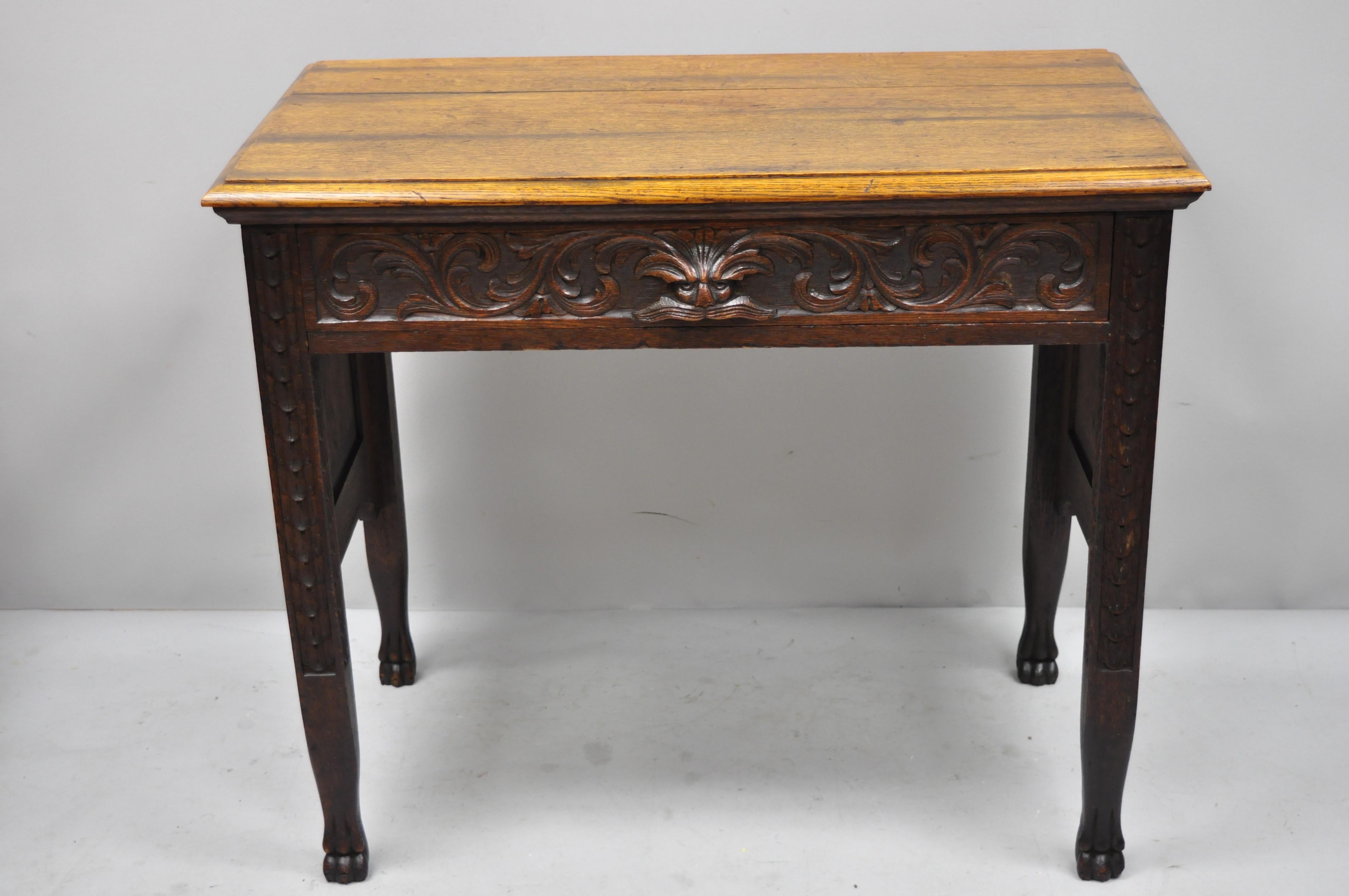 Antique black forest carved oak Jacobean mall writing desk table with Northwind face. Item features carved Northwind face drawer pull, hunter scenes to sides, paw feet, beautiful wood grain, finely carved details, 1 dovetailed drawer, circa late