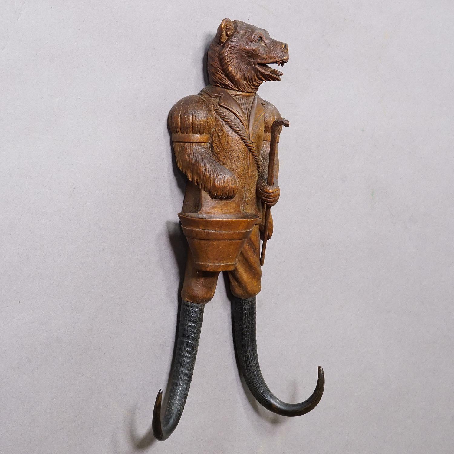 Black Forest Carved Whip Holder with Bear ca. 1900s

A very rare hand-carved coat hook or whip holder depicting a bear with a bucket and walking stick. The hooks are made from real chamois horn. Hand carved in Brienz, Switzerland, around 1900, this