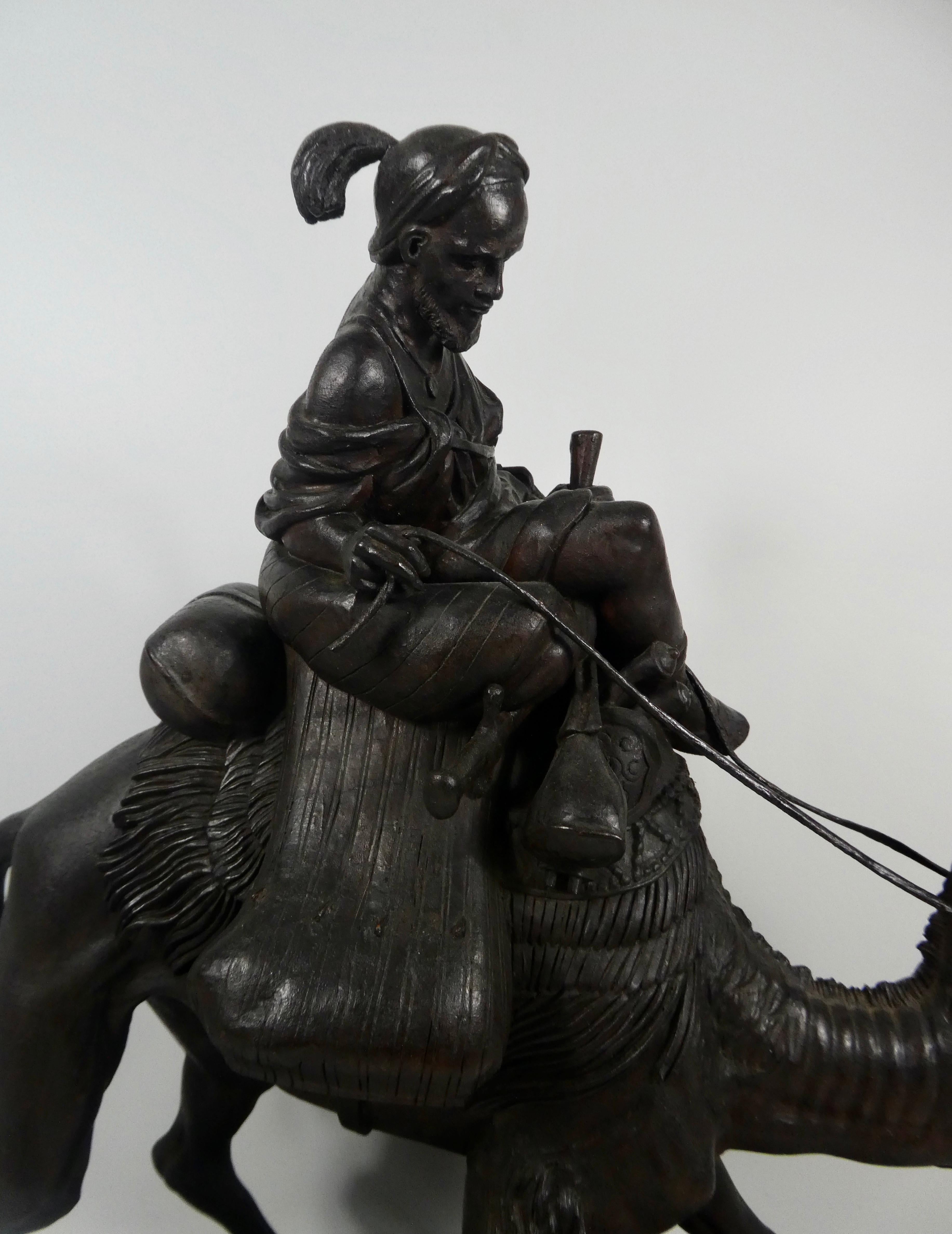 Large Black Forest carved wood group, circa 1880. Well carved as an Arab warrior riding a camel, carrying his swords, tent, and other possessions. Set upon an oval mound base, carved to simulate the desert, strewn with rocks.
Measures: Length -